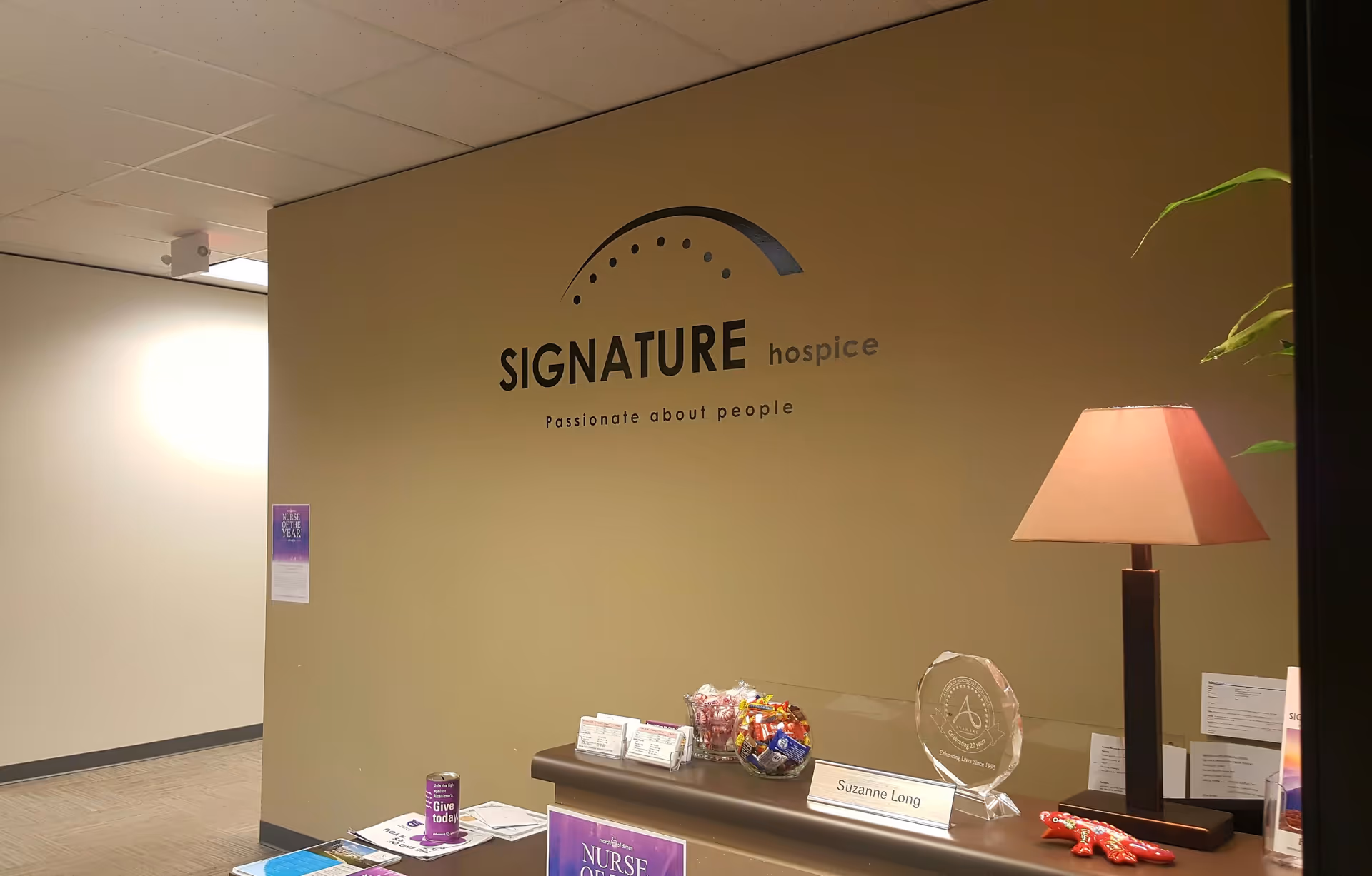 Interior reception area with Signature hospice sign and a desk against beige wall.