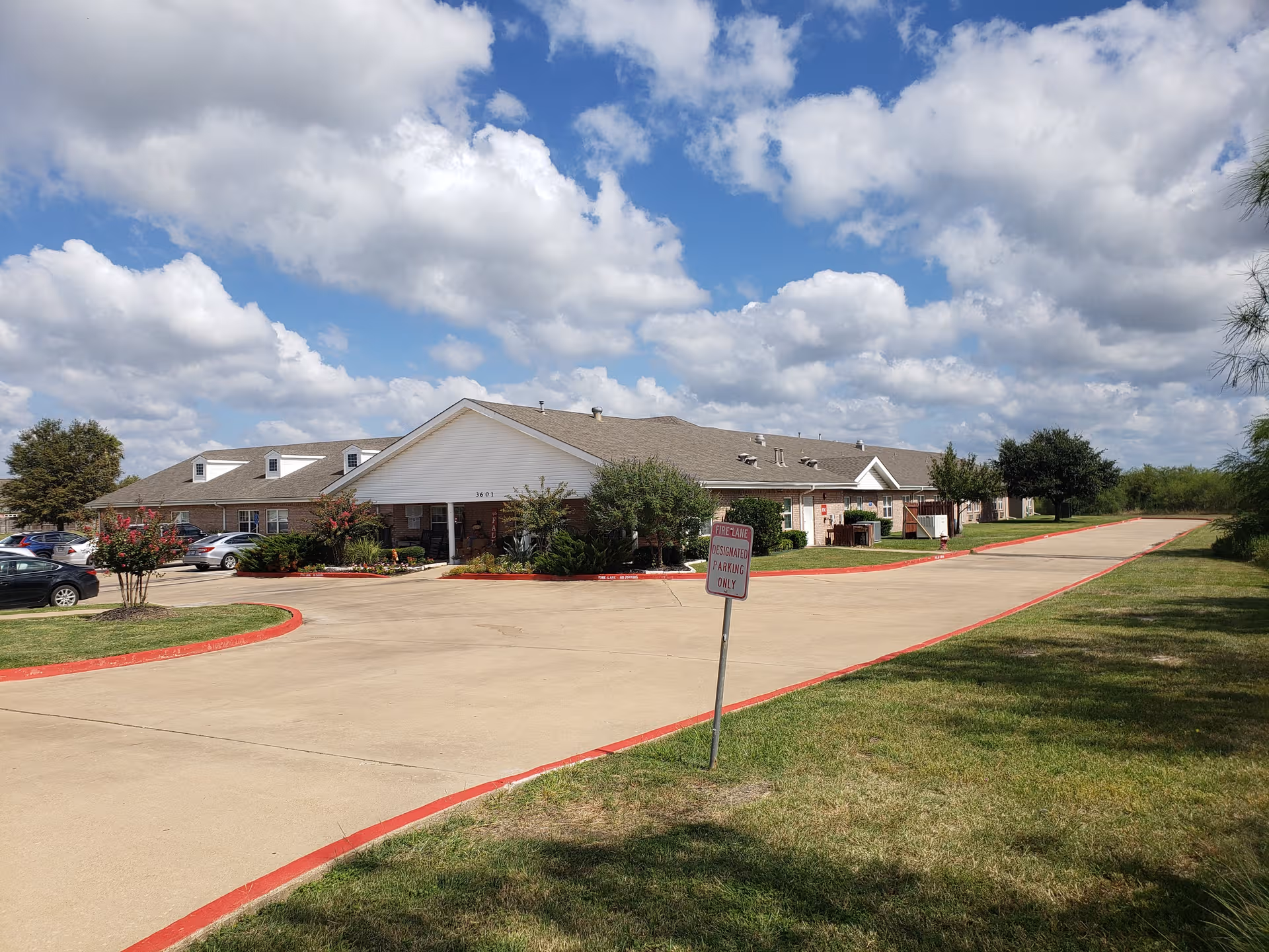 Exterior view of Bluebonnet Court senior living facility with driveway, parking, and landscaping.