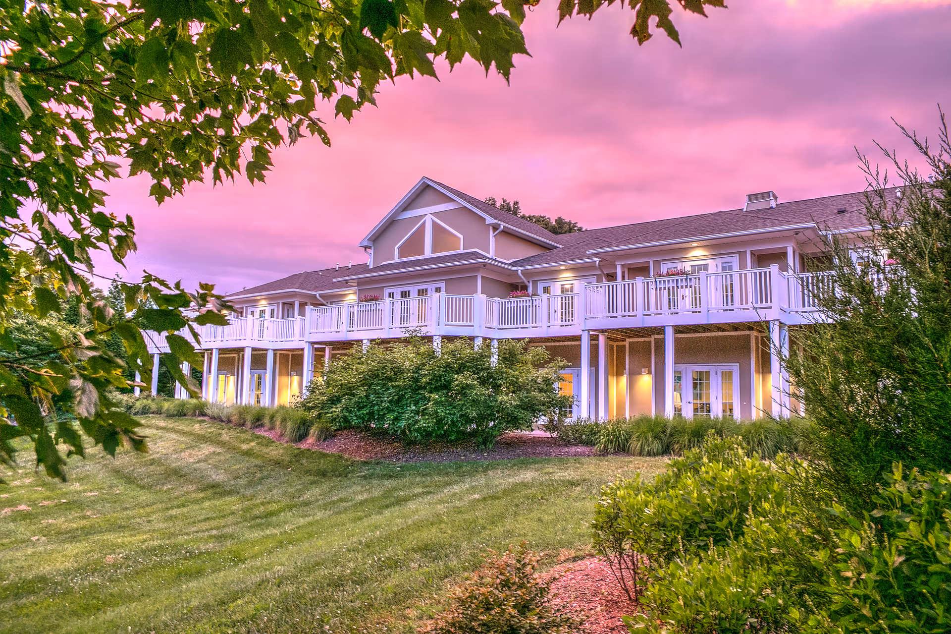 Exterior view of Burnett Calvert Hospice House with balconies and pink sunset sky.