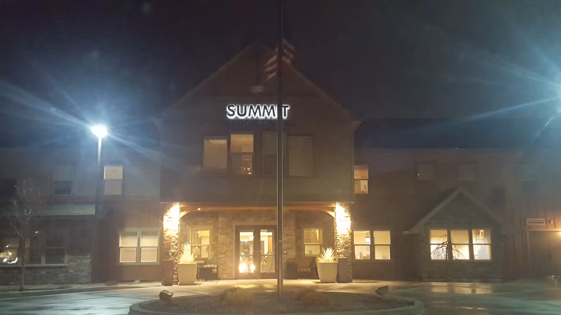 Night exterior of Summit Senior Living facility with lit entrance and stone columns