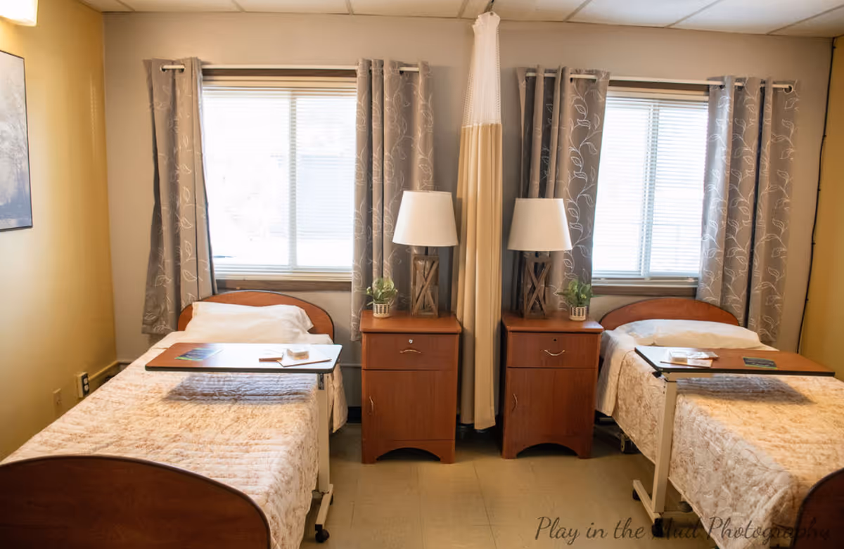 Two twin beds with matching nightstands and lamps sit on either side of a central curtain.