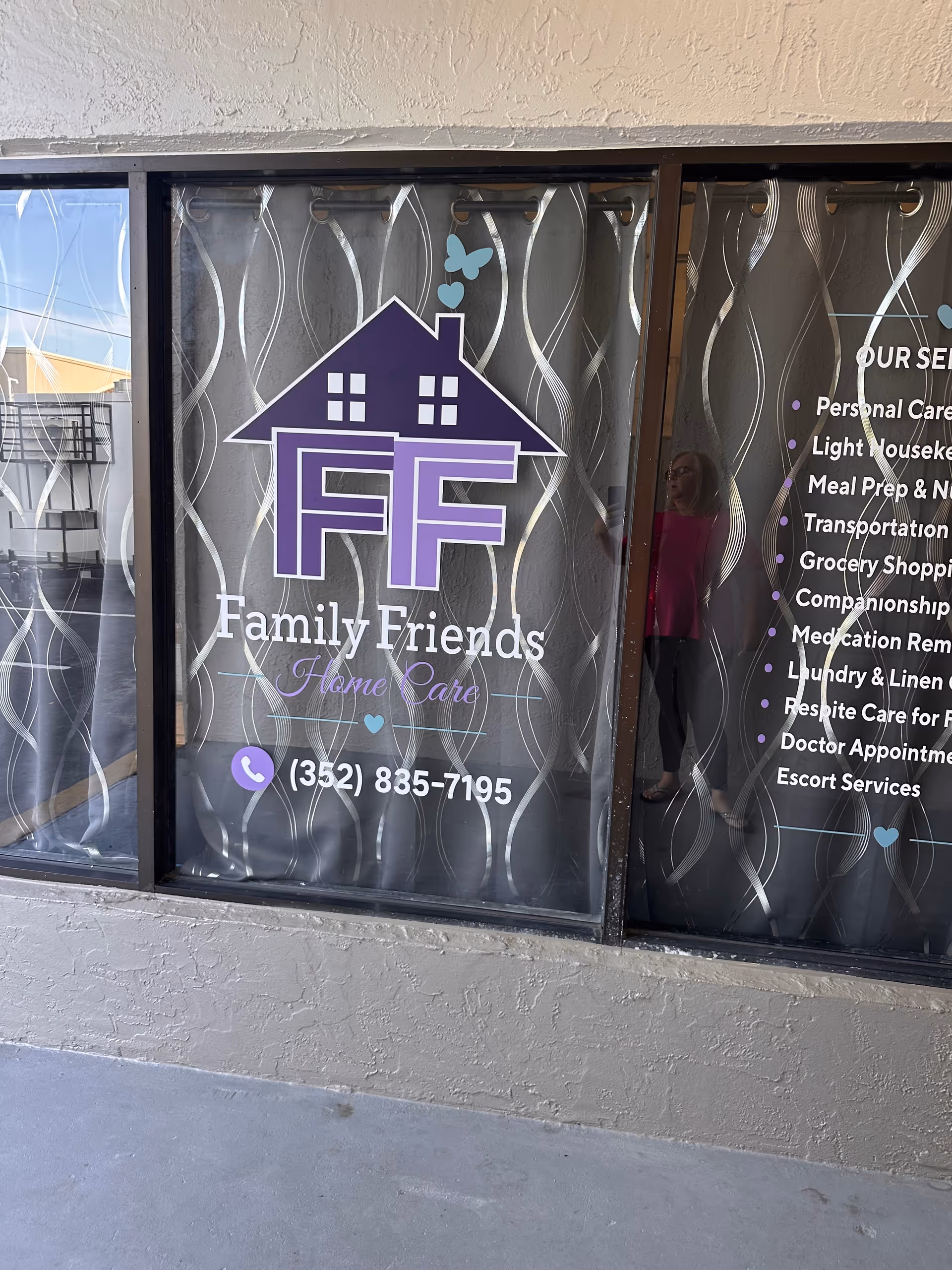 Exterior window display with purple Family Friends Home Care logo on curtains.