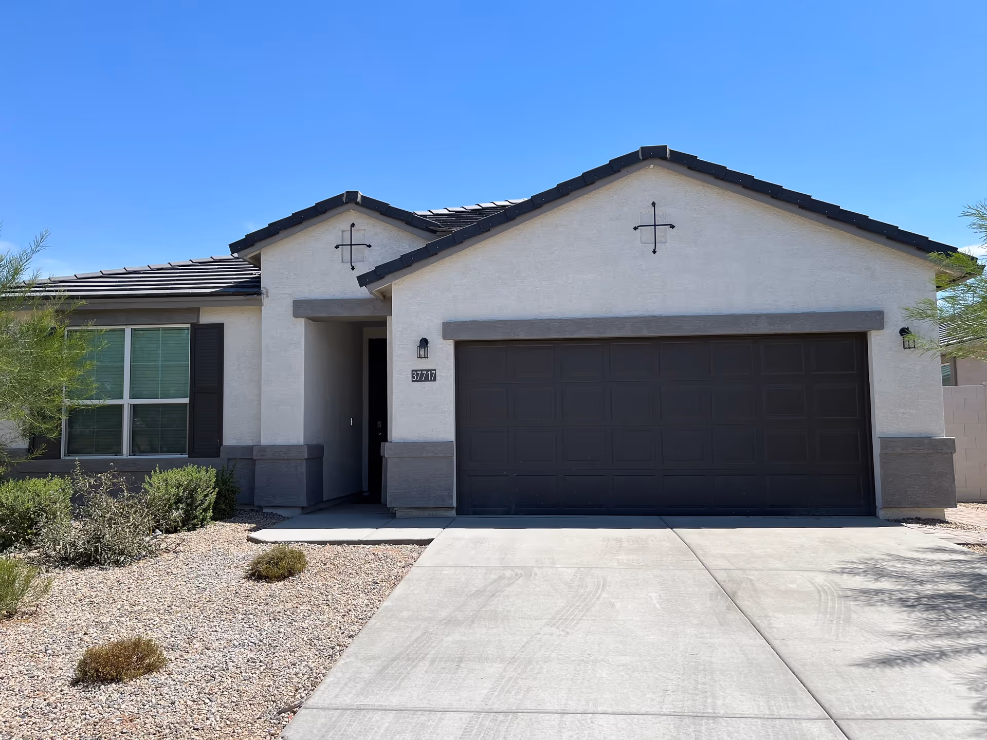 Front view of a single-story building with a two-car garage and desert landscaping