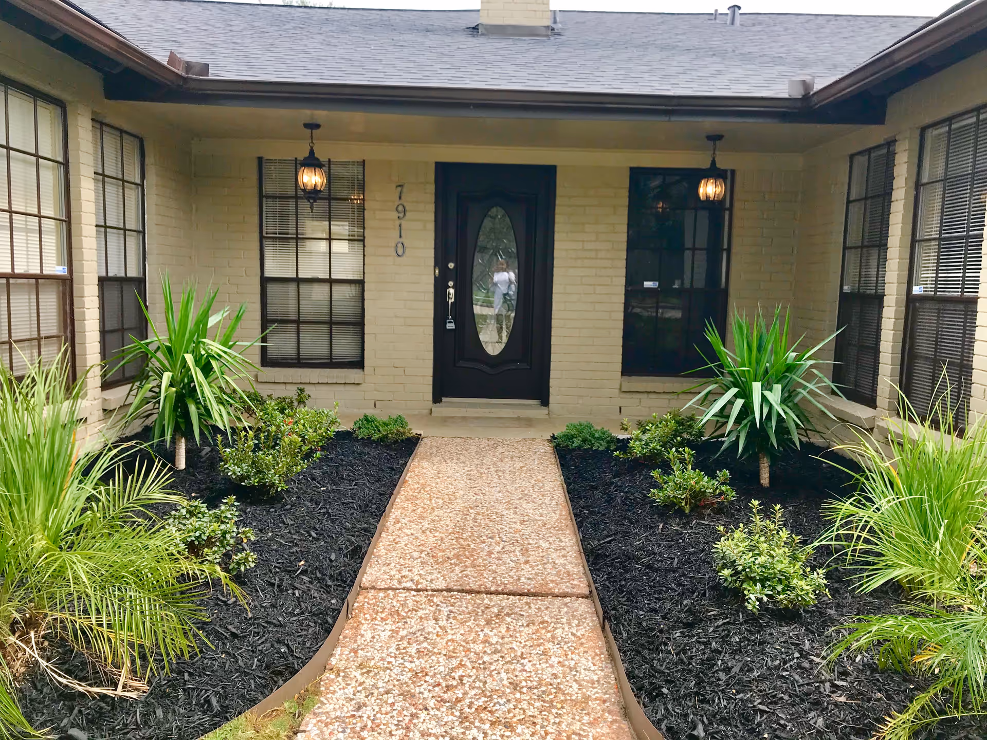 Front entrance of a beige brick senior living facility with a landscaped walkway.