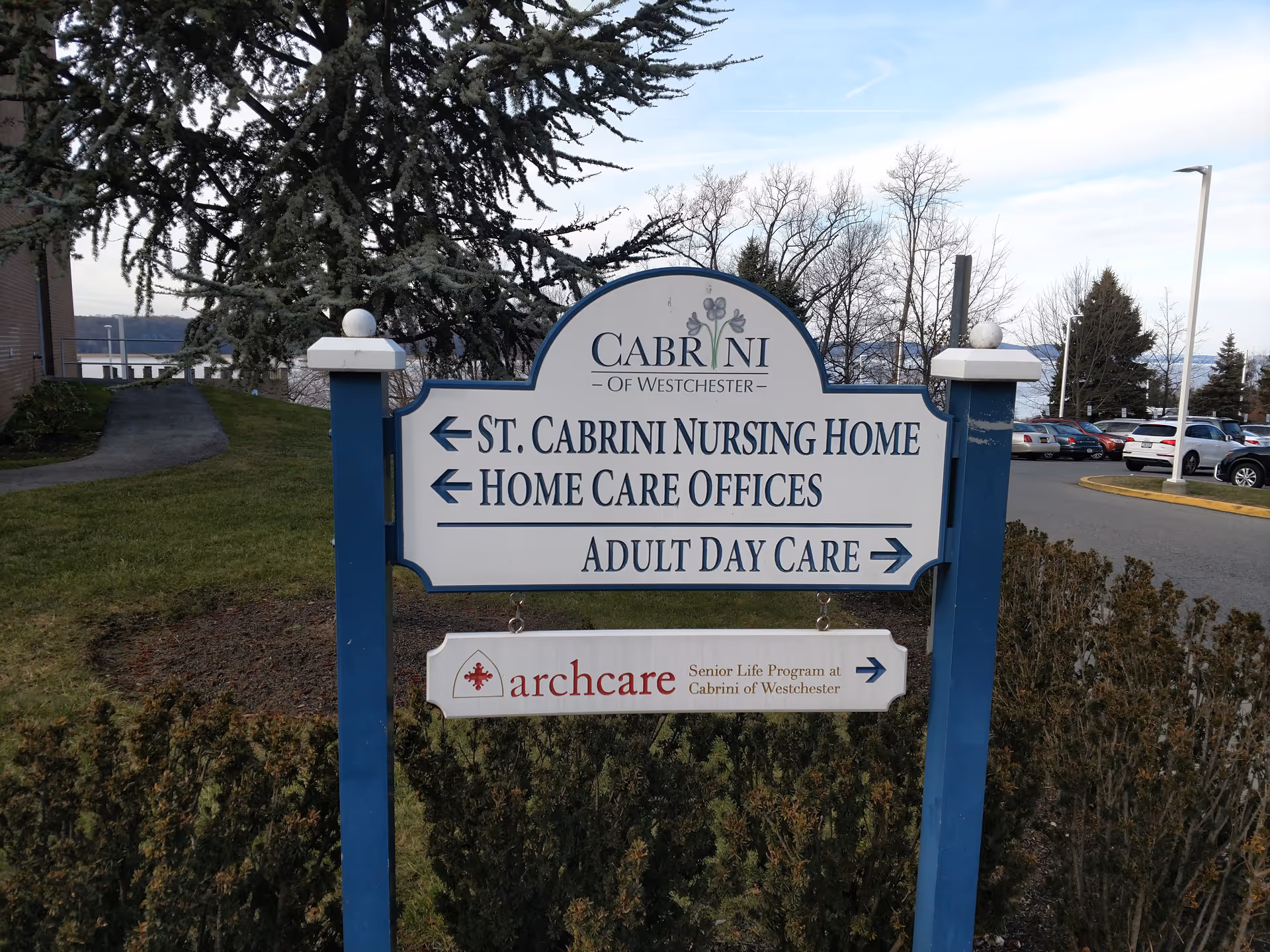 Blue and white entrance sign for St. Cabrini Nursing Home with directions.