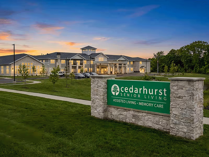 Exterior view of Cedarhurst Senior Living facility with a stone sign and lawn.