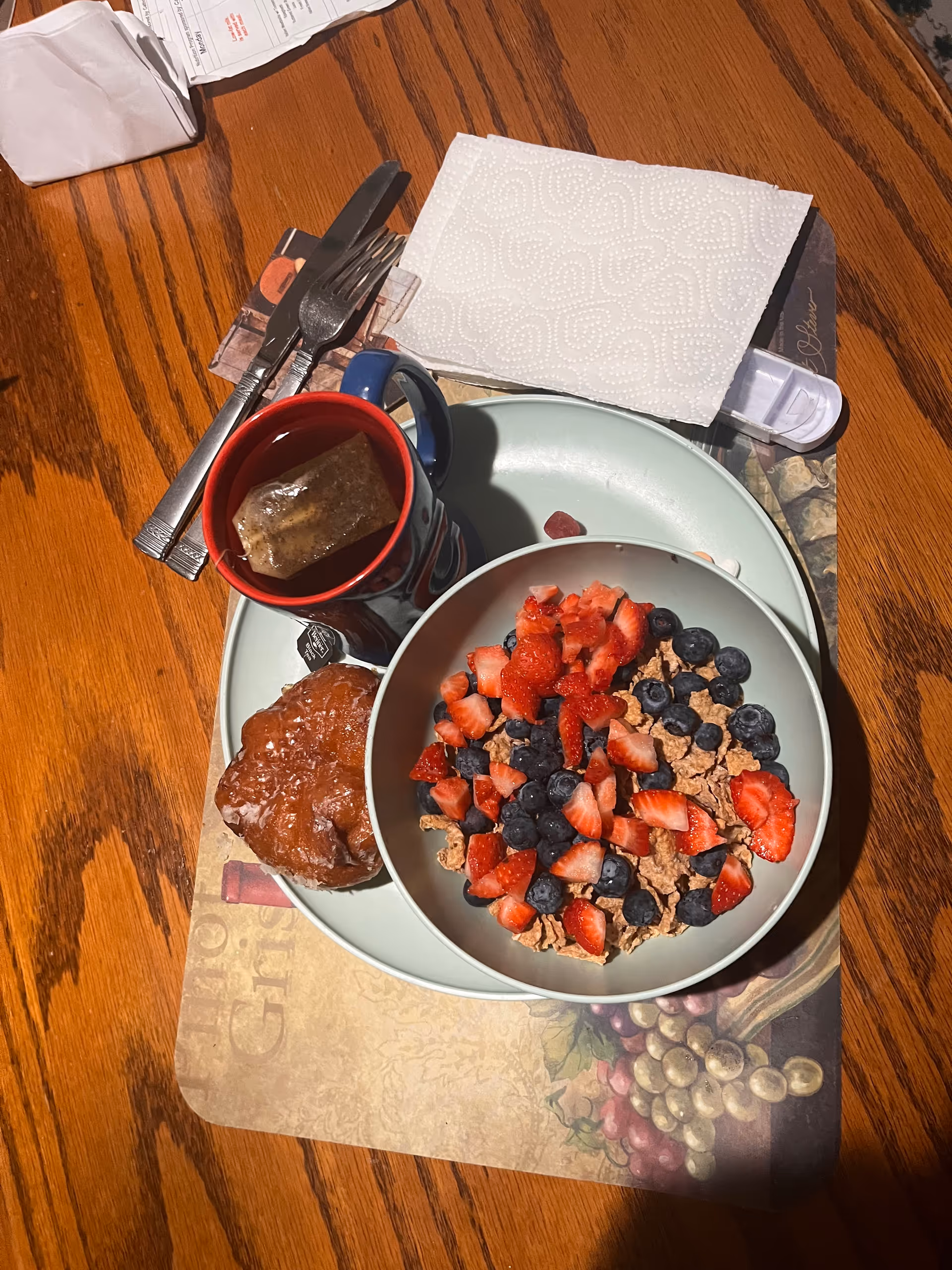 Bowl of granola with strawberries and blueberries on a wooden dining table.