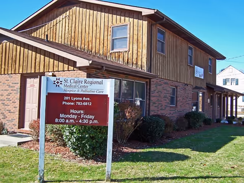 Exterior view of a two-story wood-siding building with a front sign and well-kept lawn.