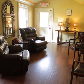 Cozy living room with leather seating, wooden floors, and a decorative ornate mirror.