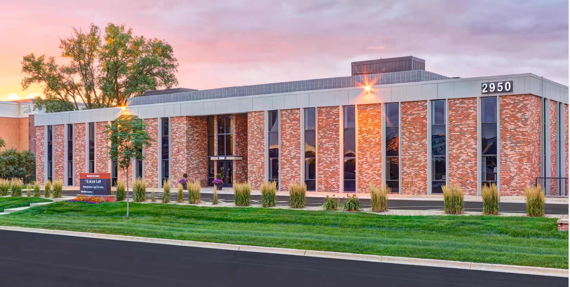 Exterior view of a brick senior living facility with tall windows and landscaped lawn.