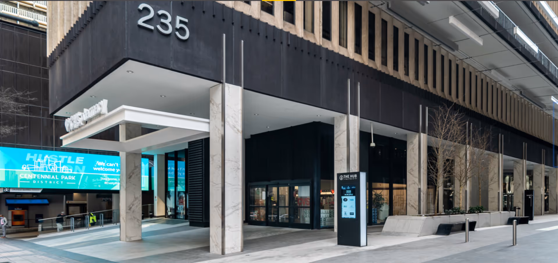 Modern building exterior with large numbers 235 and glass storefronts along a sidewalk.