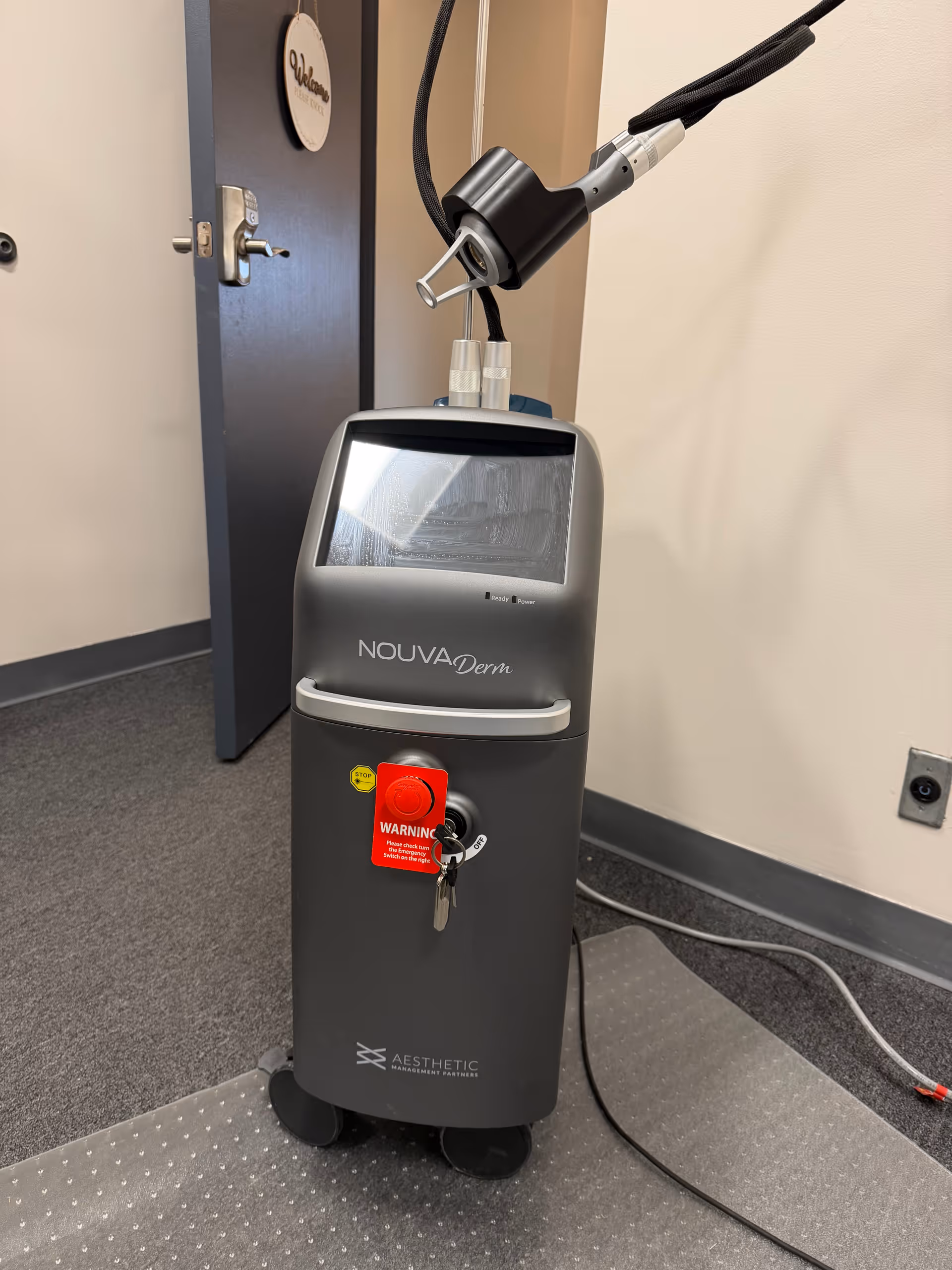NOUVA Derm medical device on wheels beside a doorway in a clinic room