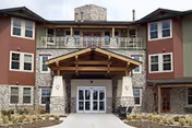 Front exterior view of Harvest Pointe senior living building with stone accents and entrance canopy.