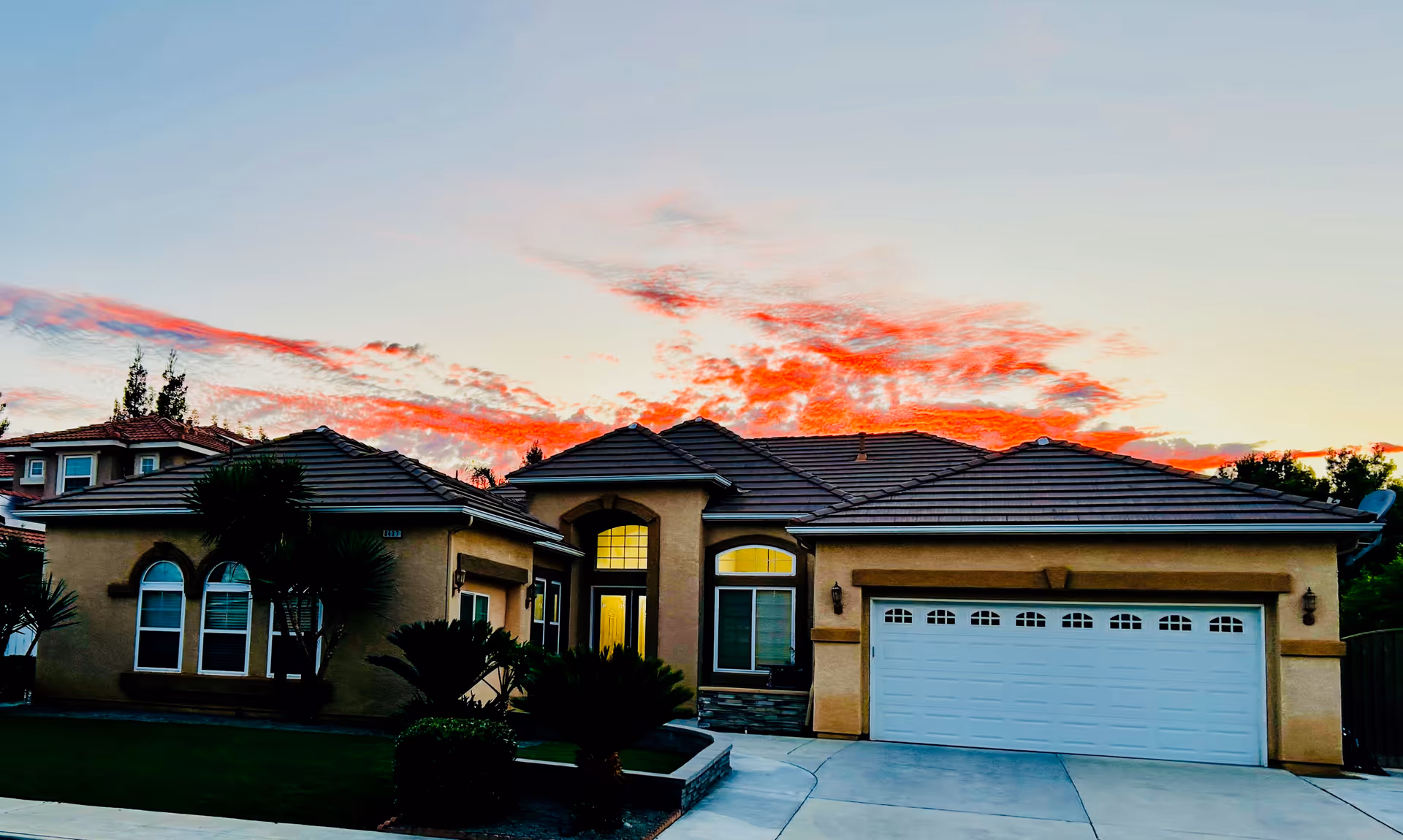A single-story beige house with a two-car garage and landscaped front yard.