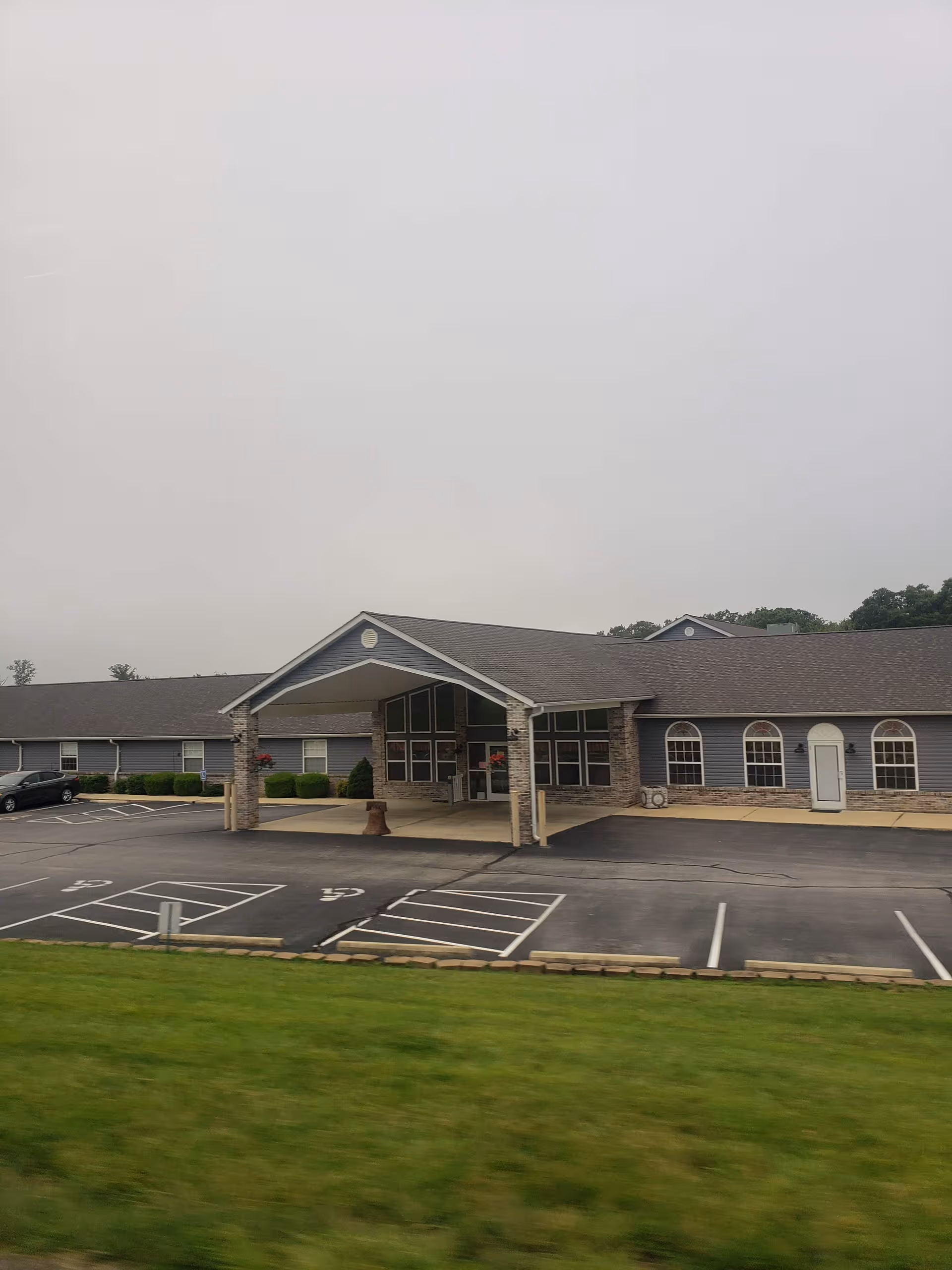 Crabapple Village Senior Estates front exterior with a covered entrance and adjacent parking lot.