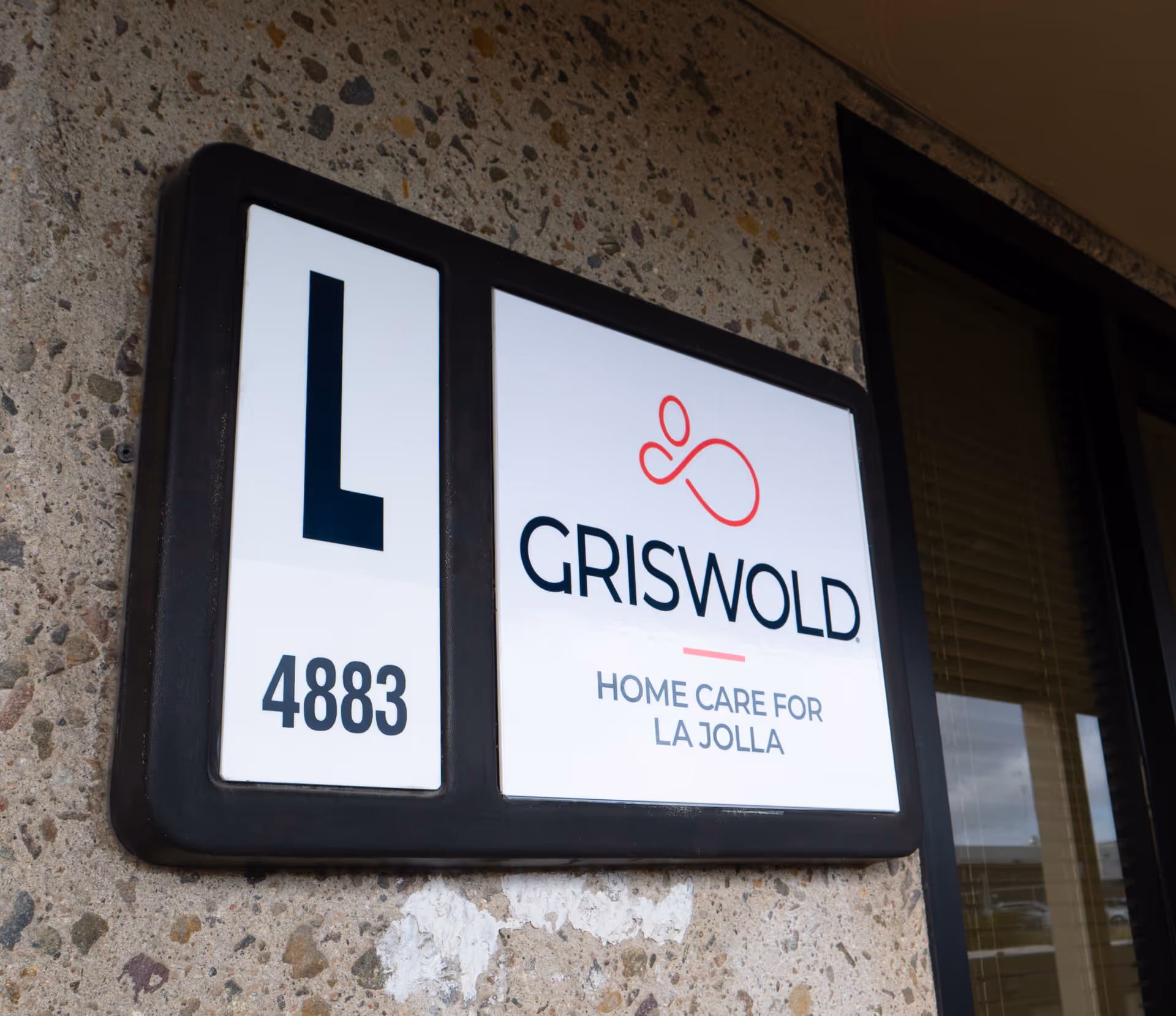 Exterior sign on a textured wall reads Griswold Home Care for La Jolla.