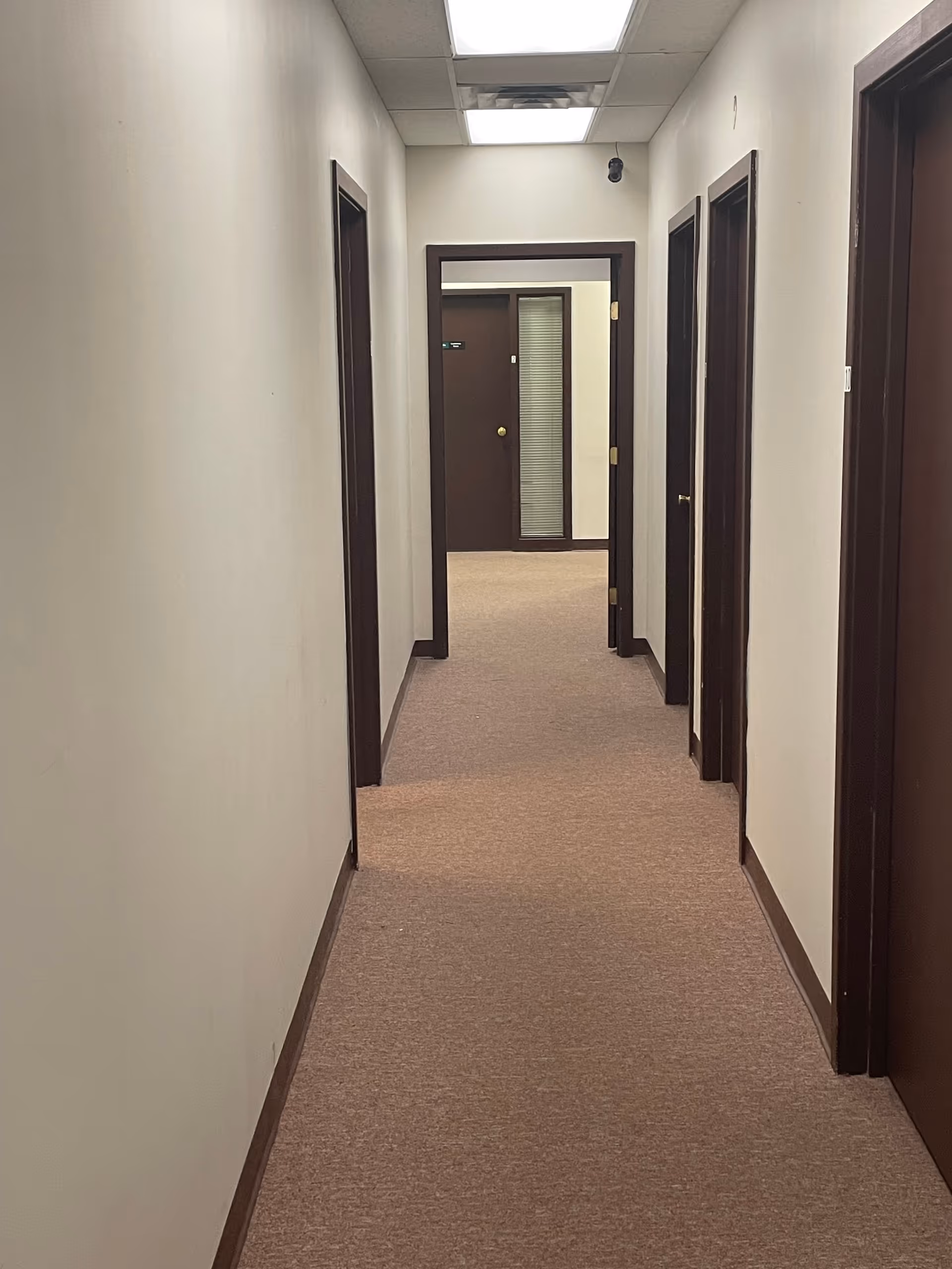 Interior corridor of a senior facility with brown-trimmed doors and ceiling lights