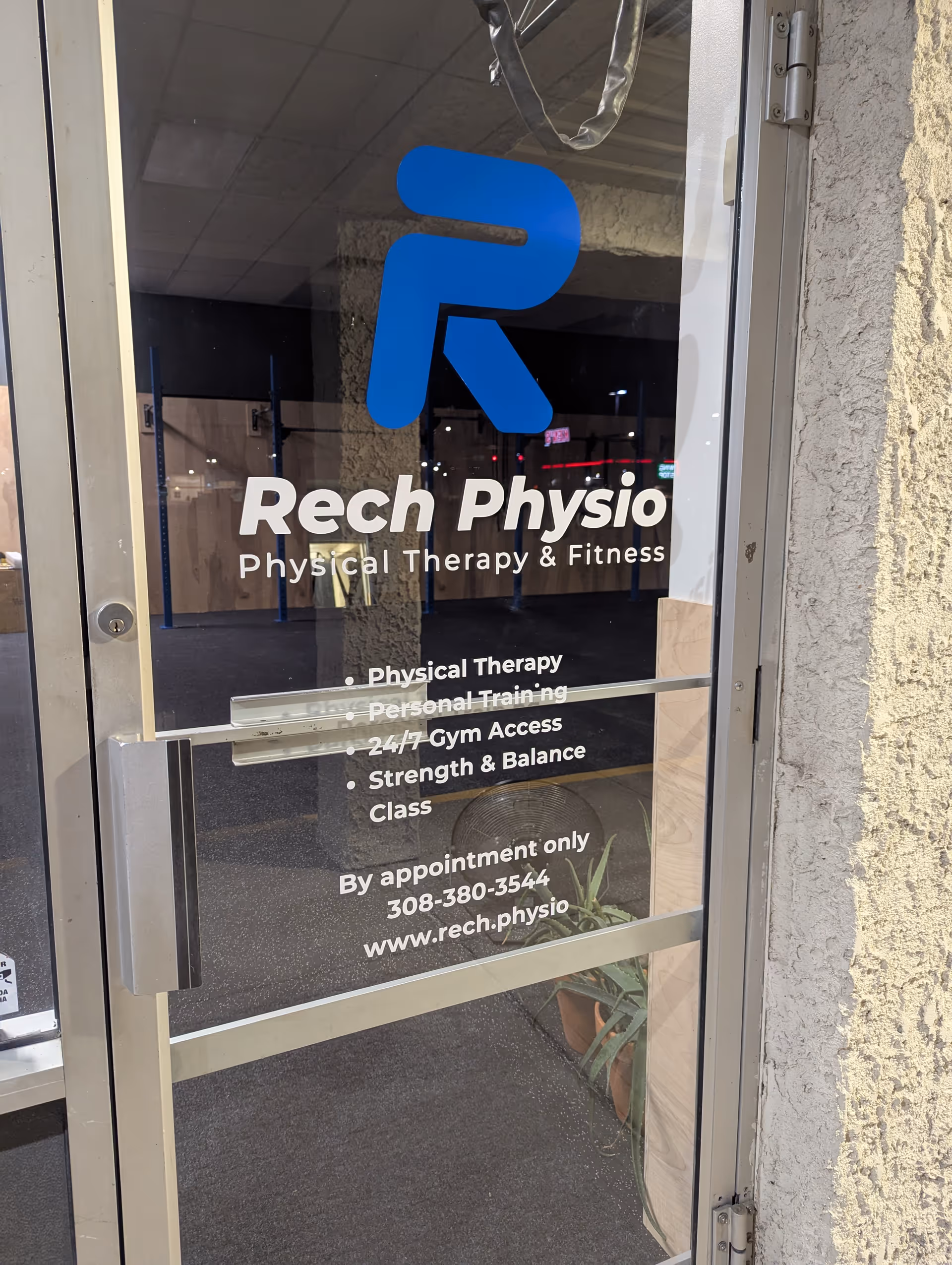 Glass door displays Rech Physio Physical Therapy & Fitness sign at building entrance.