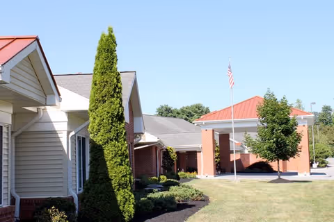 Exterior view of Havens At Princeton with brick buildings, flagpole, and manicured lawn.