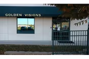 White exterior building with a blue awning, window, and door; Golden Visions sign.