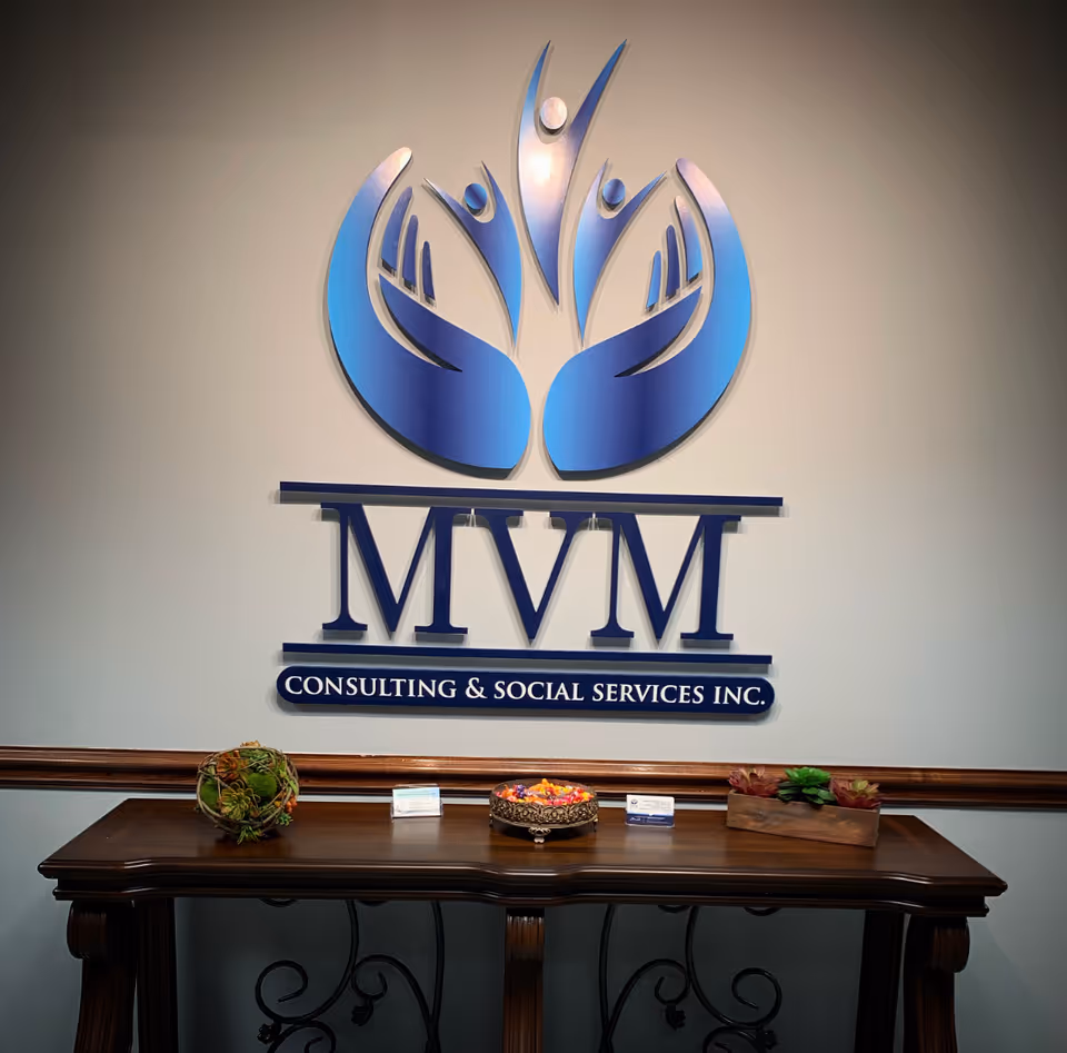 Interior wall displays a large MVM logo with a wooden reception table and plants.