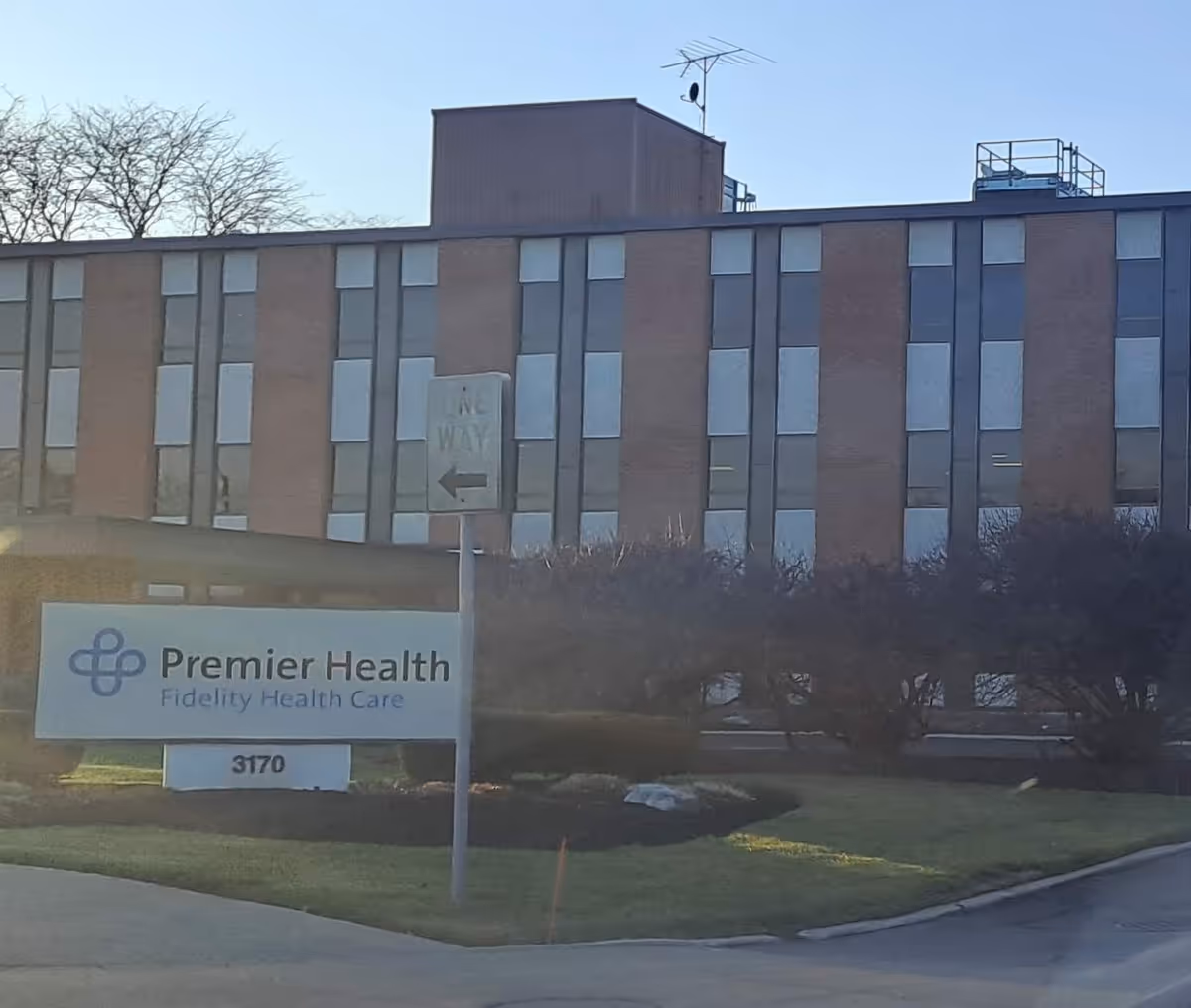 Multi-story brick building with a Premier Health Fidelity Health Care sign in front.
