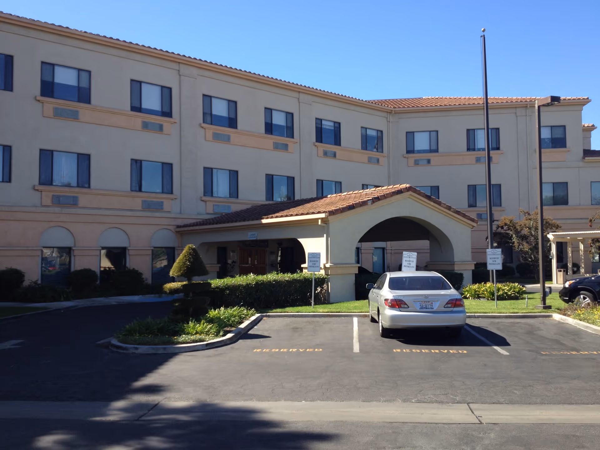 Three-story beige ManorCare exterior with tiled entrance canopy and a parking lot.