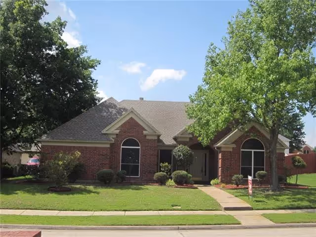 Front view of a single-story red brick house with a lawn, walkway, and trees.