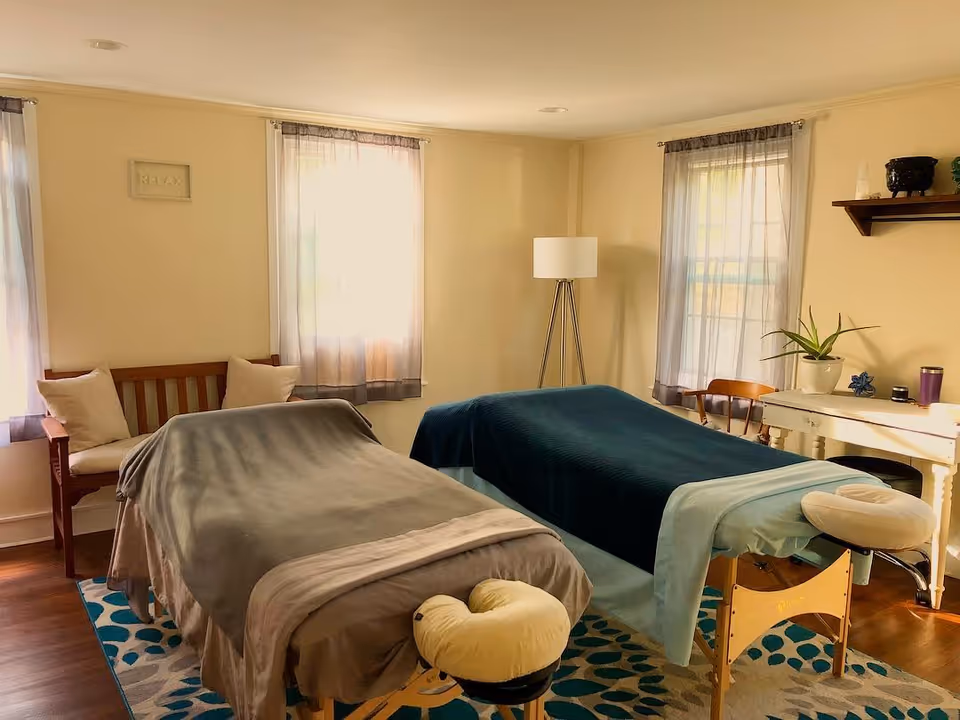 Two massage tables in a sunlit therapy room inside a senior living facility.
