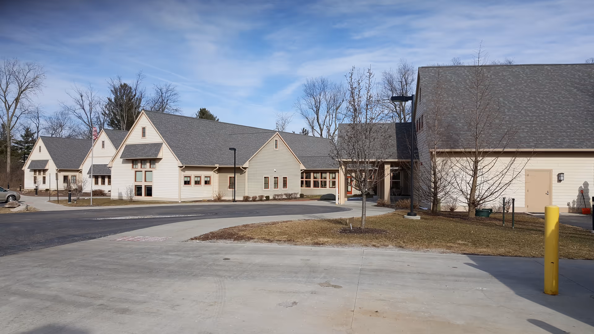 Exterior view of a beige senior living campus with connected buildings and a paved driveway.