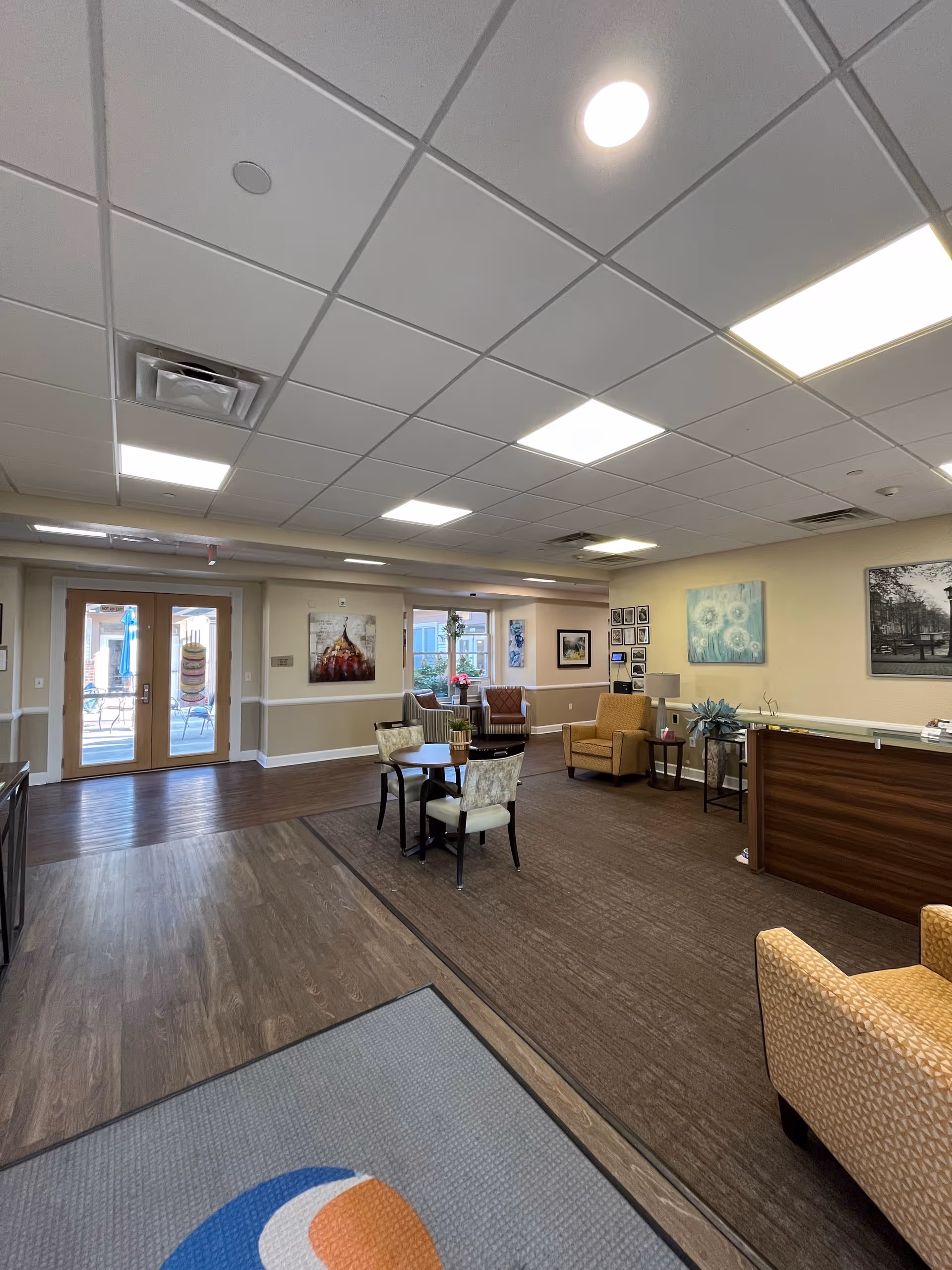 Lobby area of Vibrant Life Senior Living with seating, tables, and wall art.