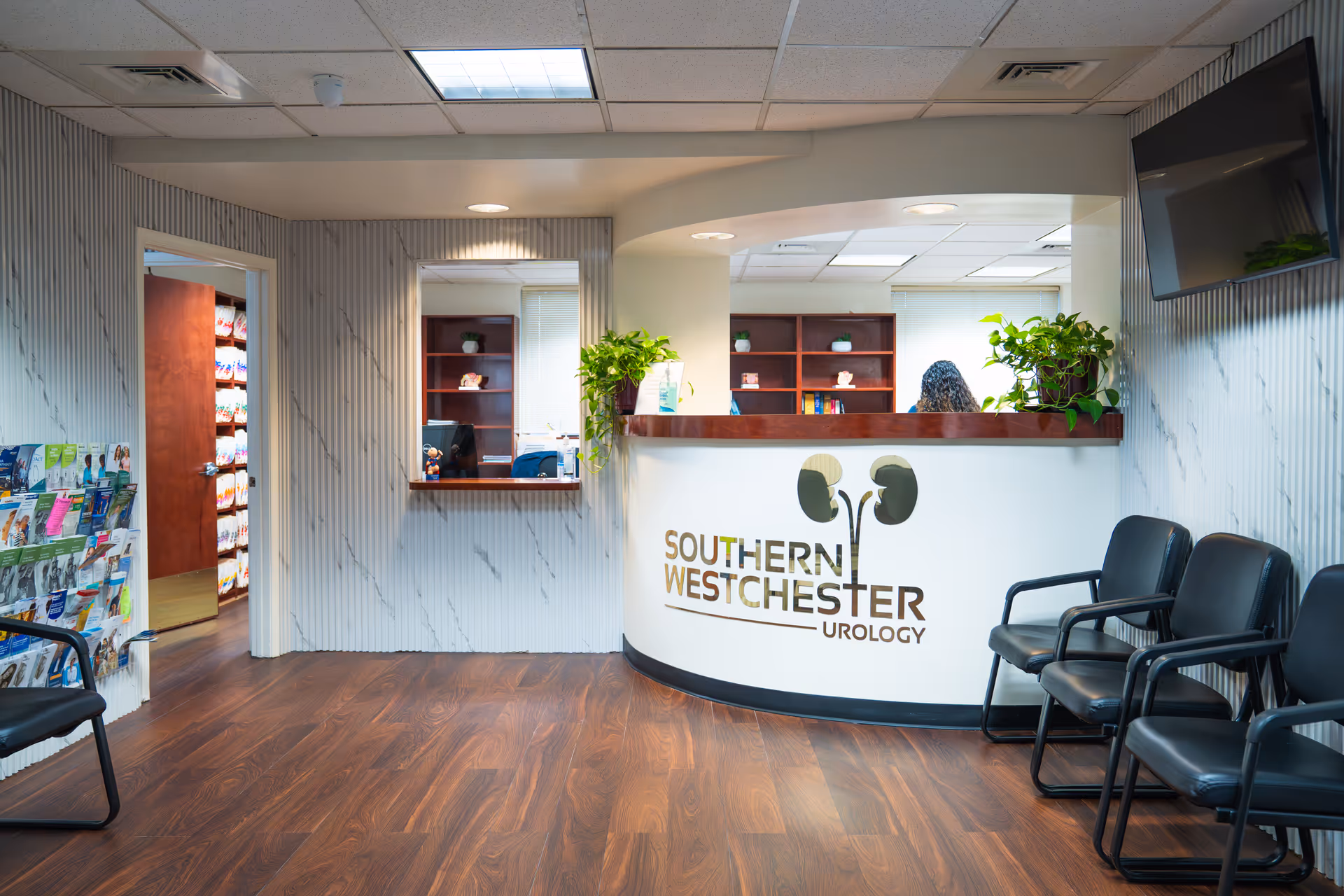 Reception desk with Southern Westchester Urology logo, chairs, and plants in a lobby.