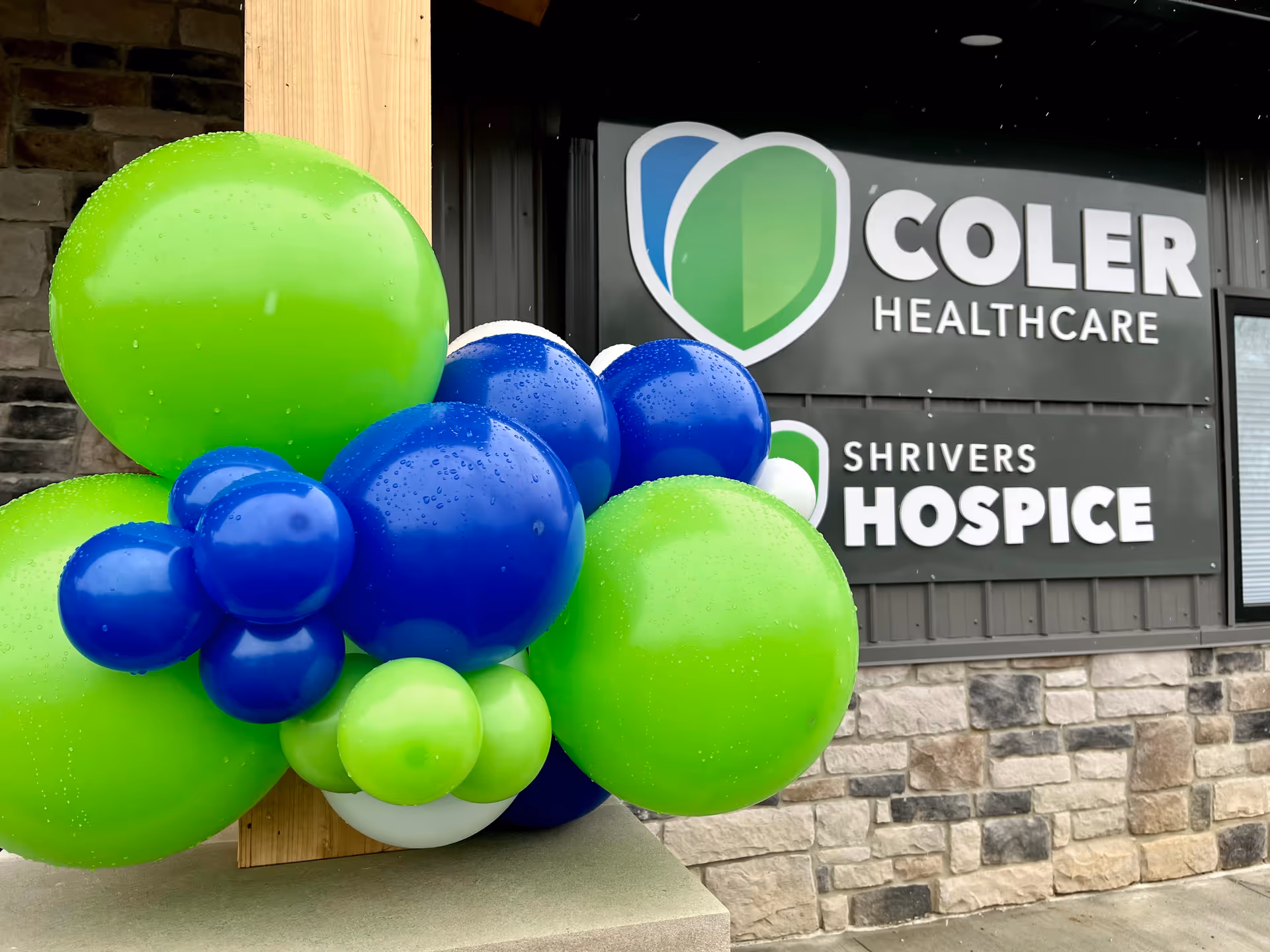 Exterior view of Shrivers Hospice building with green and blue balloons in foreground