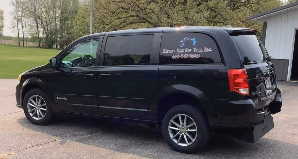 A black van with Kares - Just For You, Inc. branding parked outdoors.