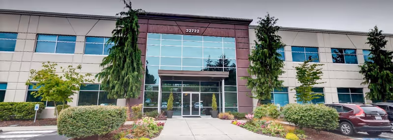 Front exterior view of a two-story facility with glass entrance and landscaping.