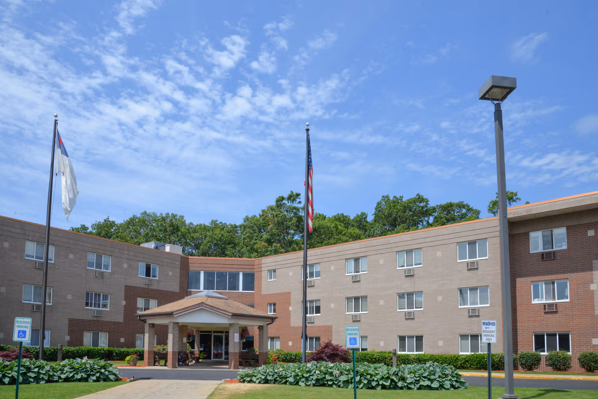 Exterior view of Christian Care Assisted Living building with entrance, flags, and landscaping.
