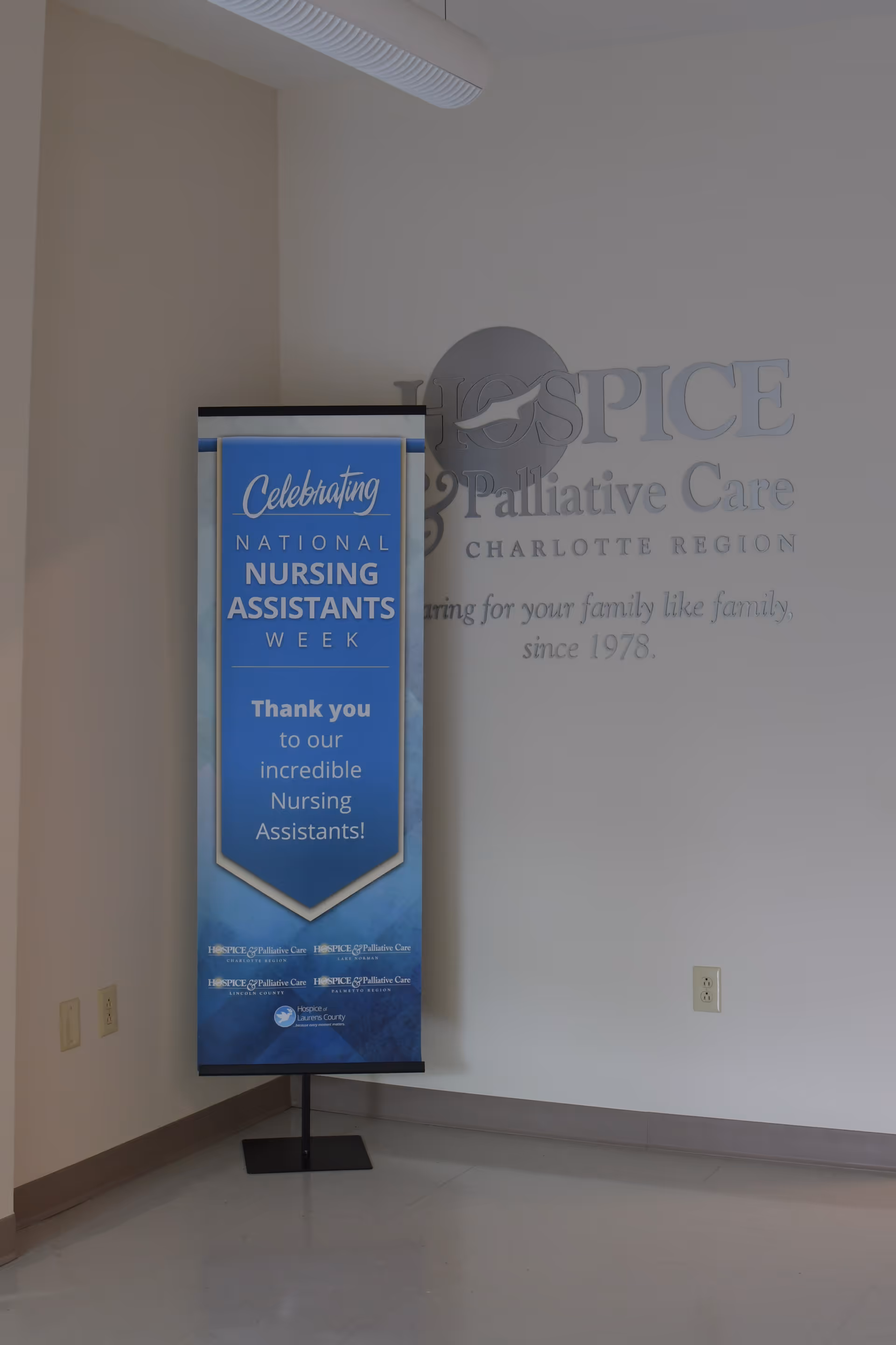 Blue nursing banner beside a hospice wall sign inside a facility.