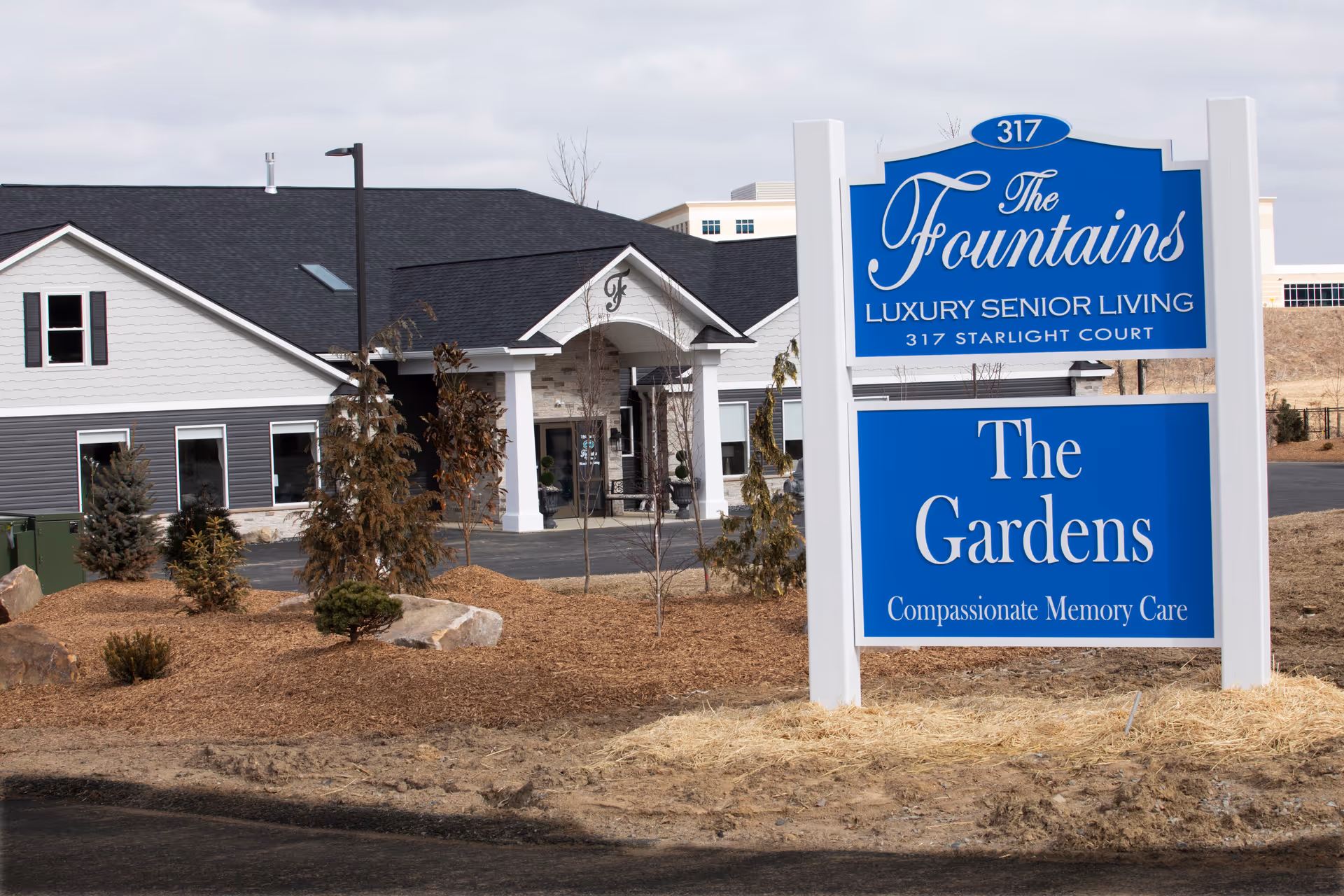 Exterior view of The Gardens at Latrobe with blue sign and entrance.