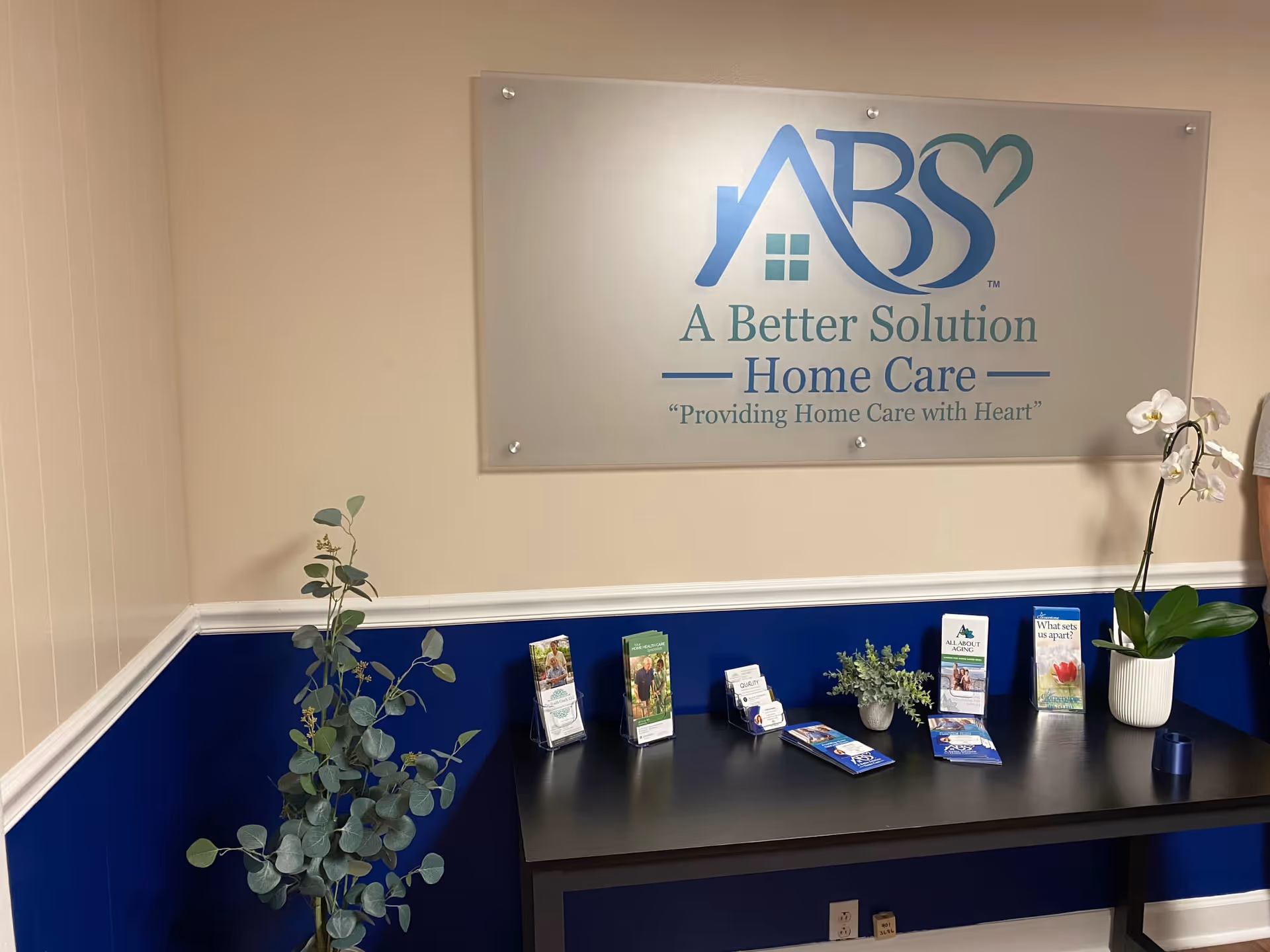 Reception area with a sign reading A Better Solution Home Care and brochure table.