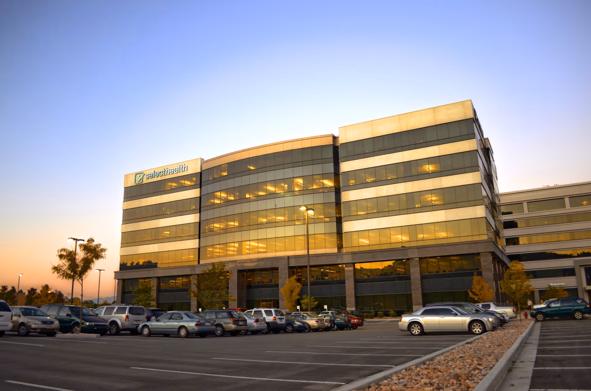 Front view of a Select Health building with glass facade and a parking lot.