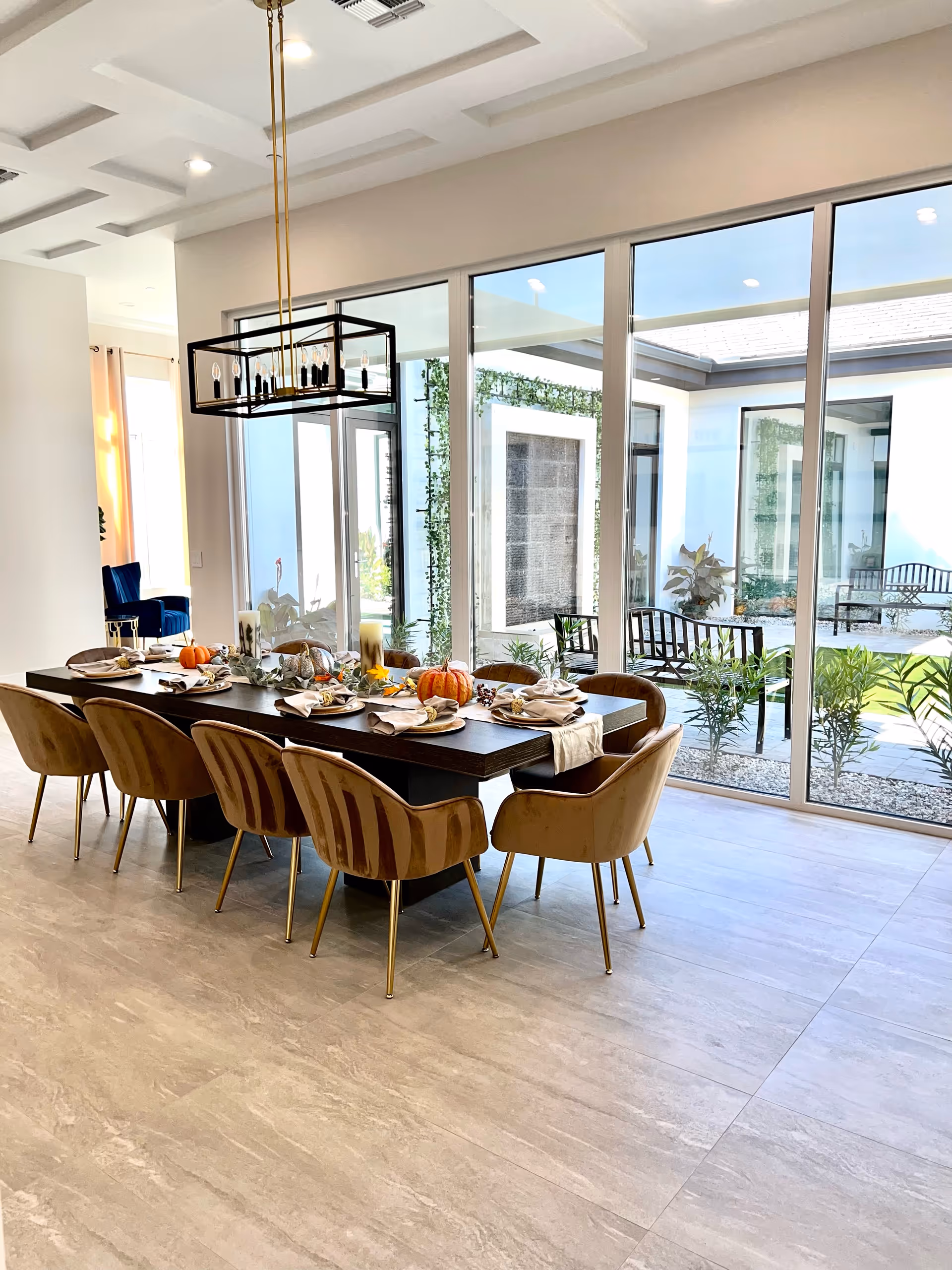 Bright dining room with a long table, place settings, and glass doors opening to the outdoors.