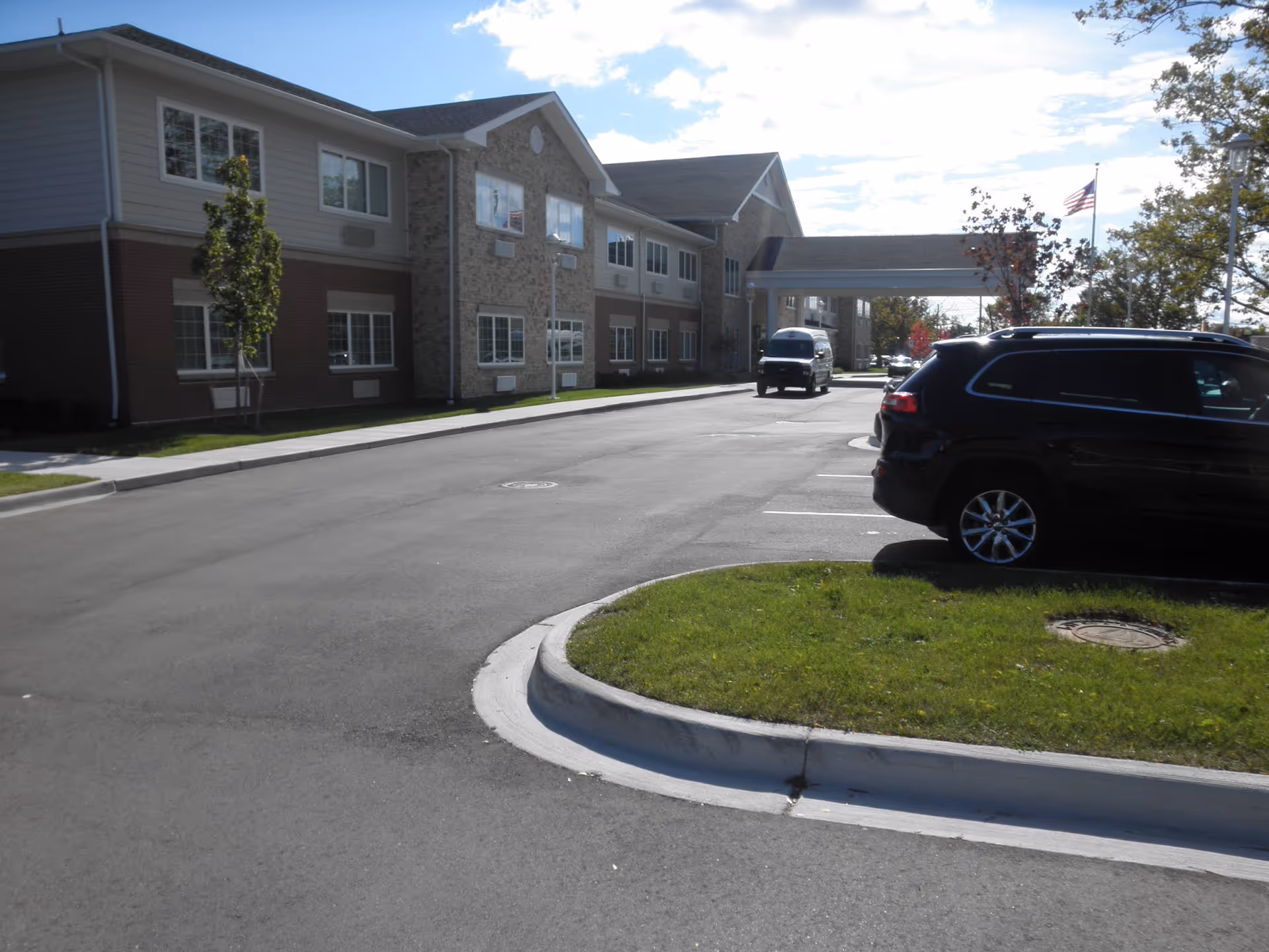 Senior living facility exterior with a parking lot and covered entrance.