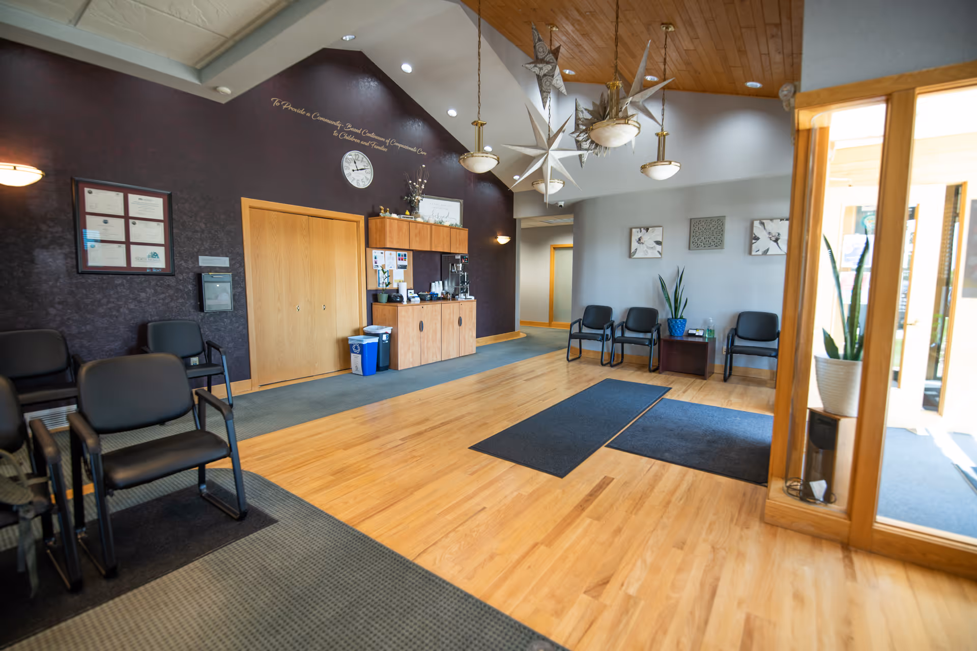 Spacious lobby with wooden floor, black chairs, and a reception area.