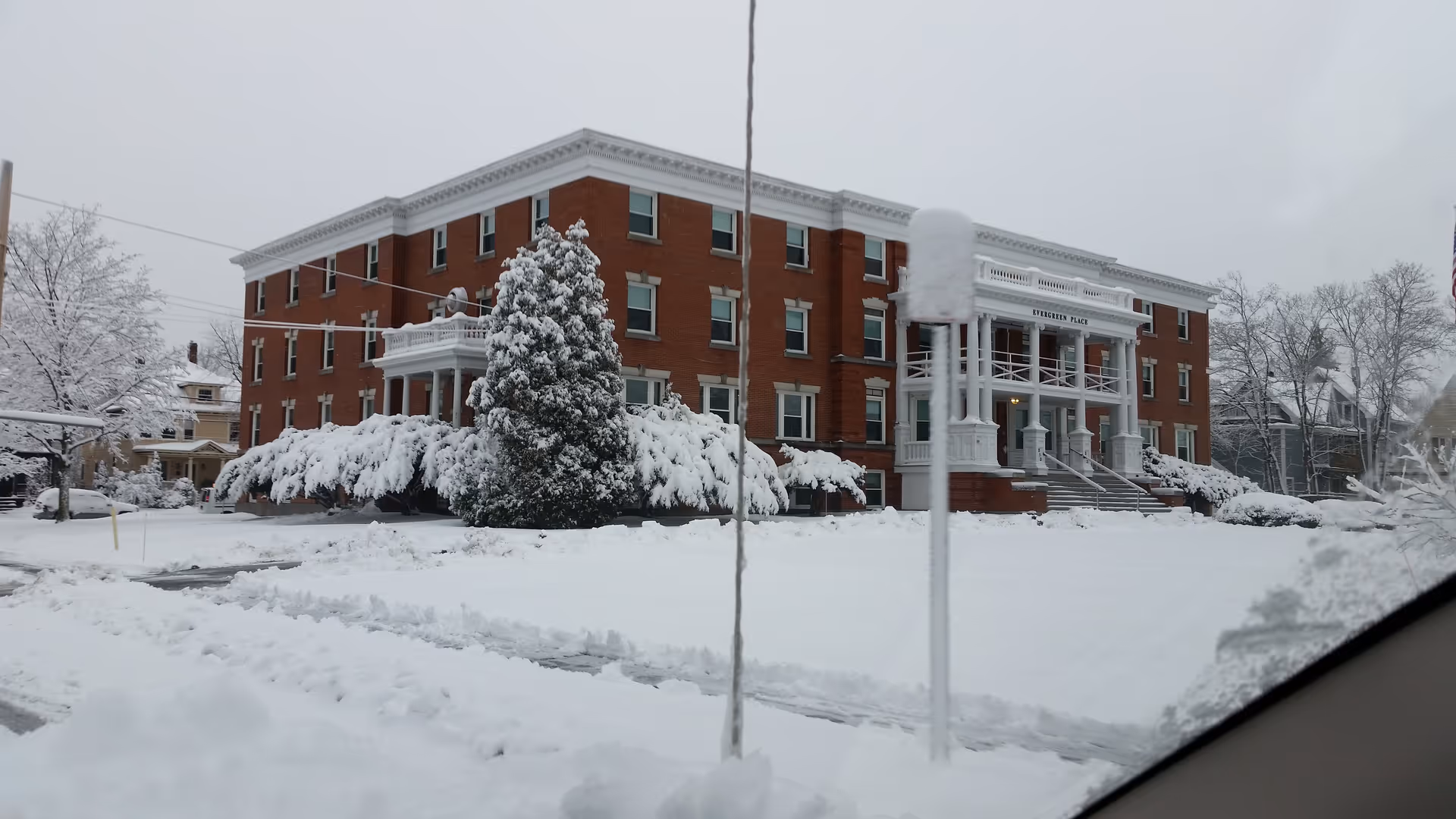 Brick Evergreen Place senior living facility with snow-covered lawn and front entrance.
