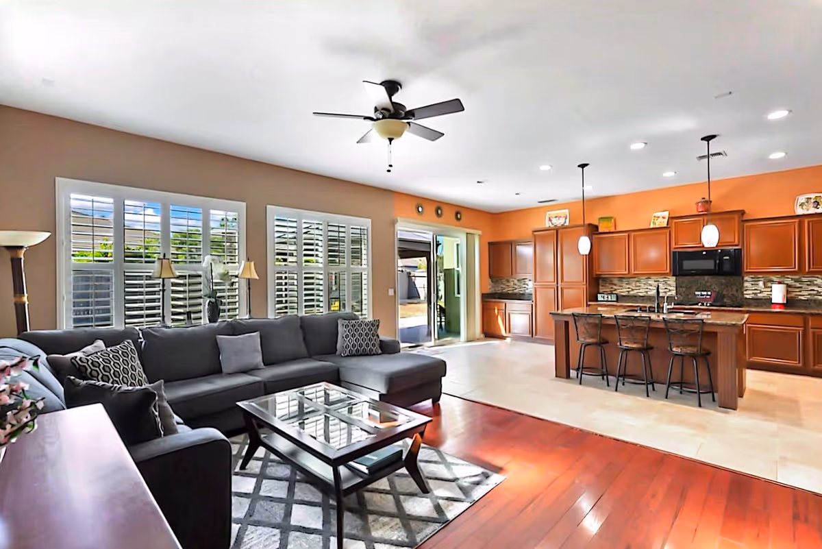 Spacious living area with sectional sofa, glass coffee table, and open kitchen.