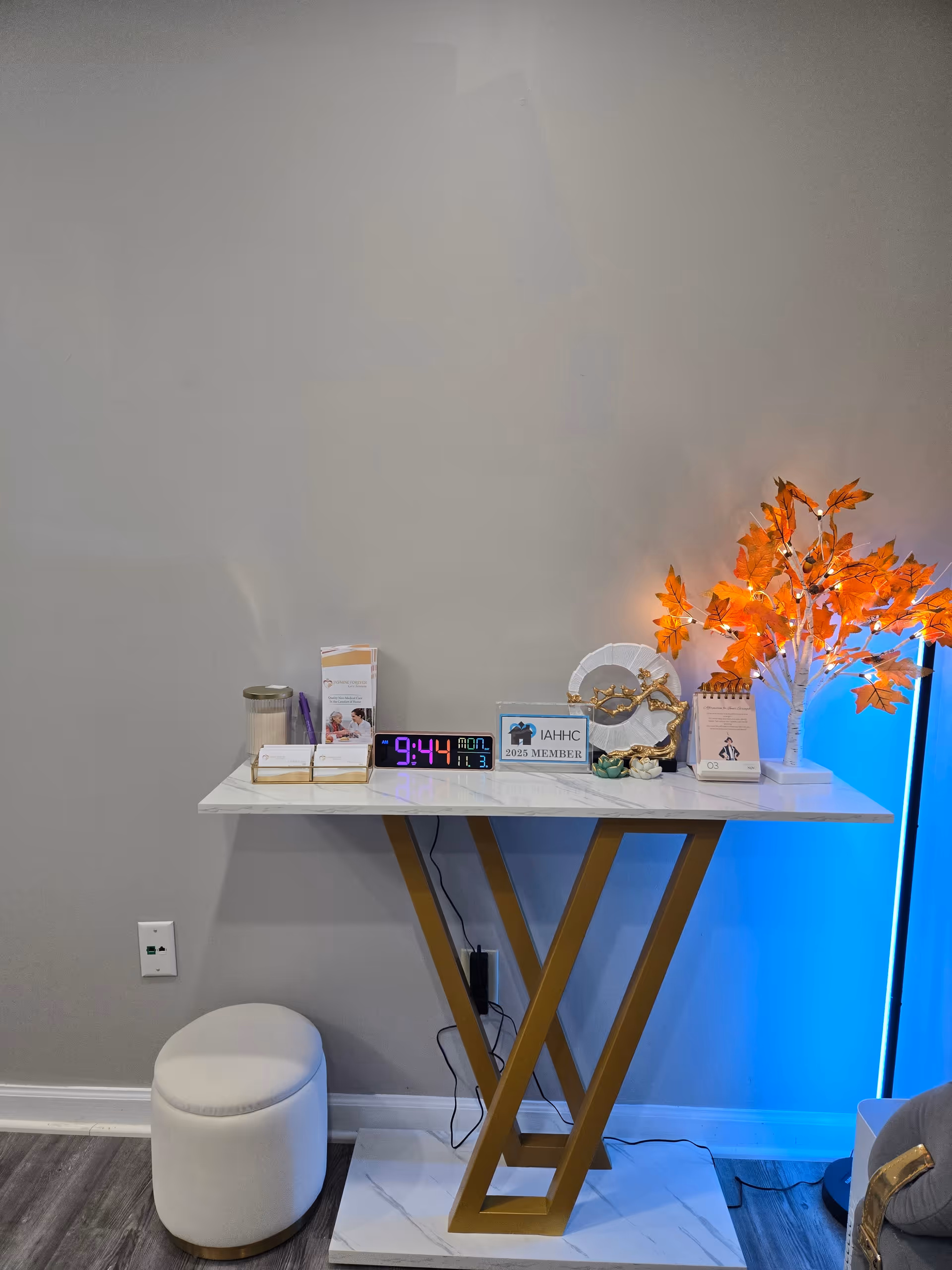 Console table with decorative items and orange foliage against a grey wall.