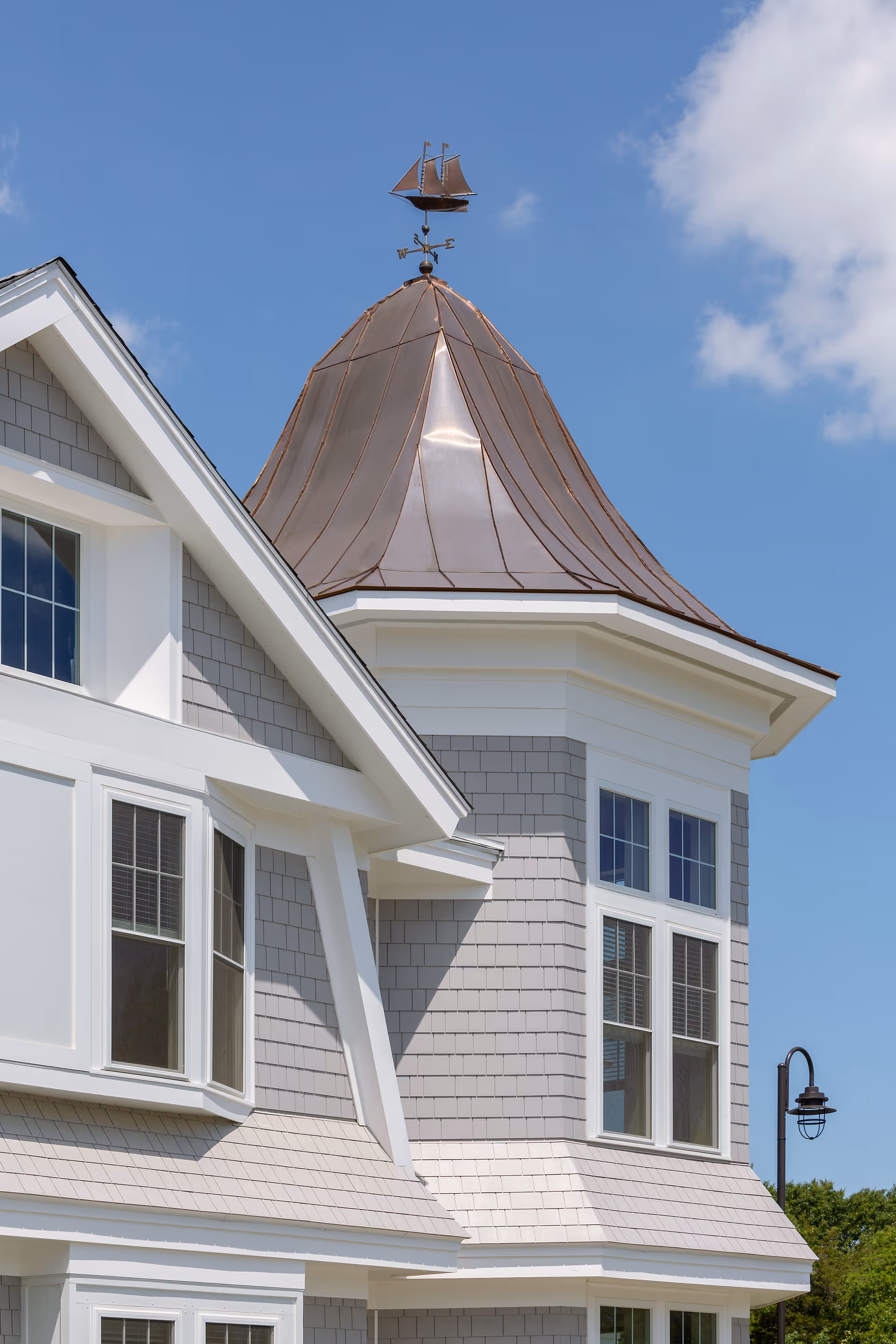 White and gray senior living building exterior with copper conical turret under blue sky.