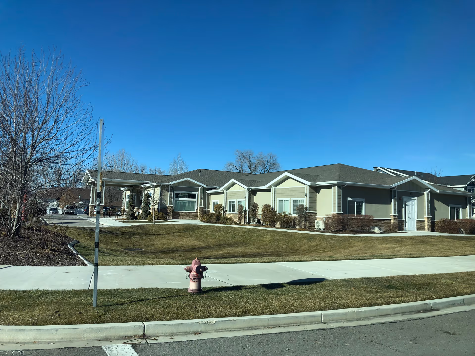 Exterior view of BeeHive Homes of Orem: a single-story senior living facility along a sidewalk.