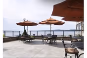 Outdoor patio with tables, chairs, and large umbrellas overlooking a water view