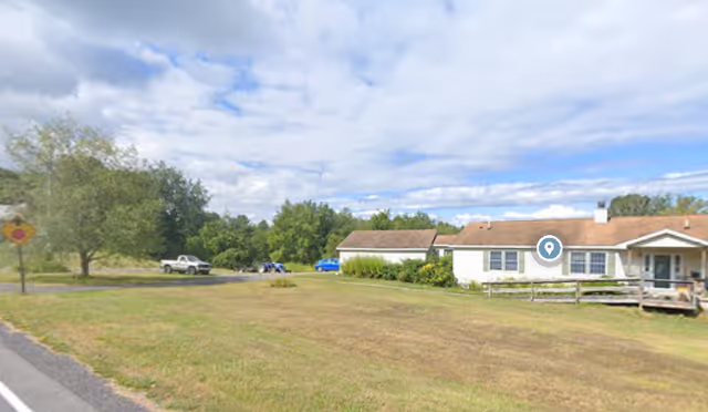 Single-story senior living facility with a grassy front yard and parked cars.